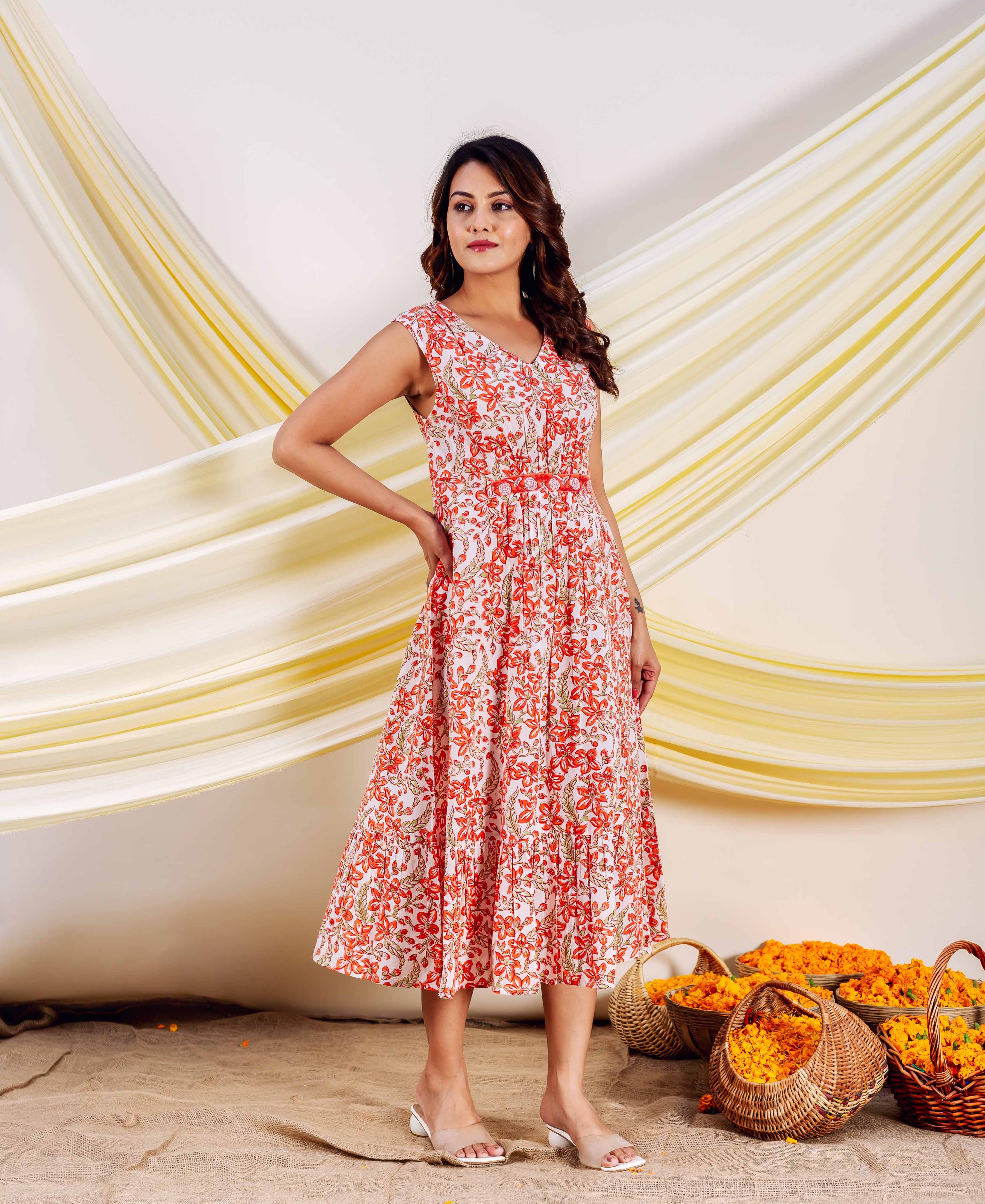 Model wearing sleeveless white dress with orange and green floral hand block print.