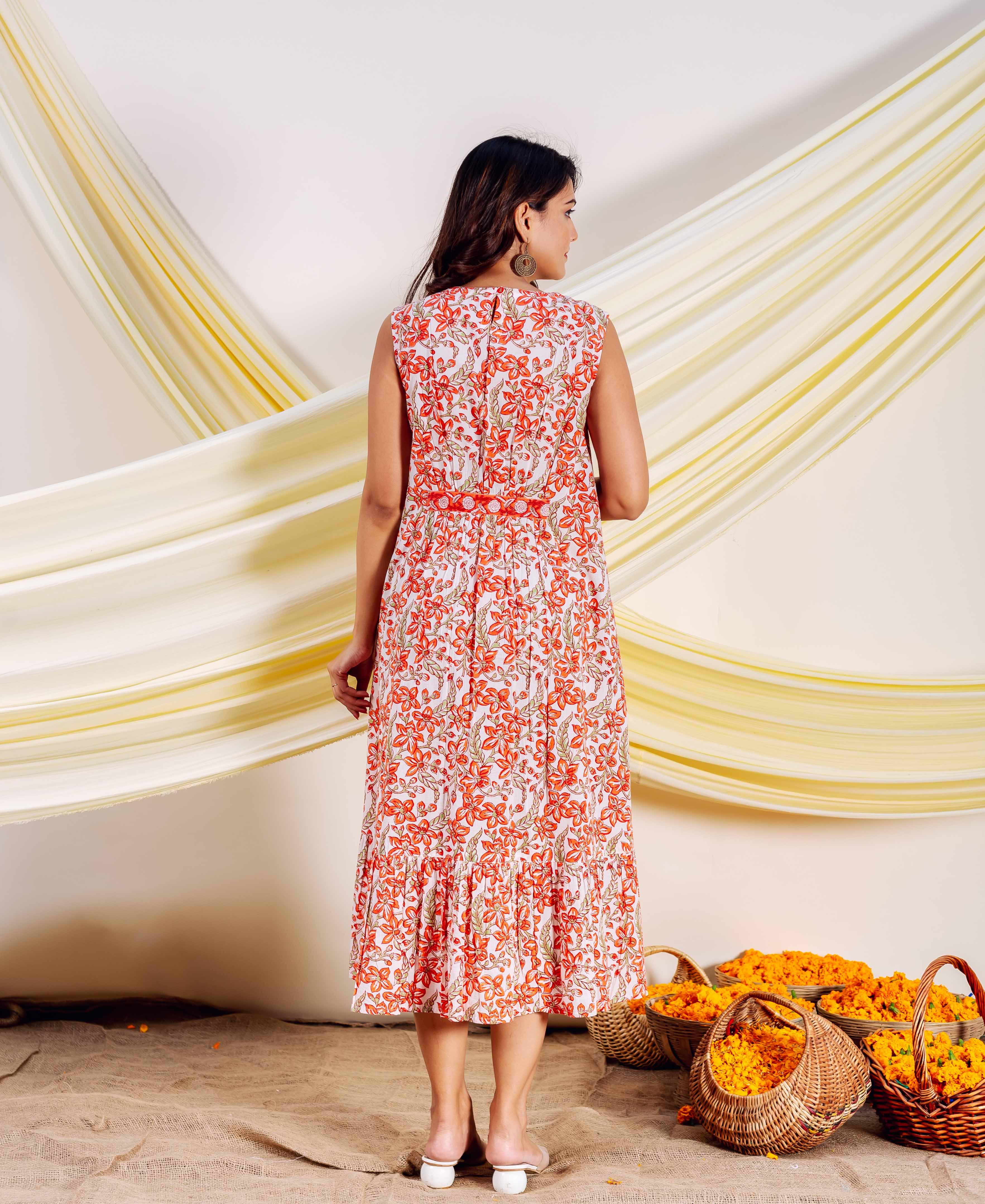 Model from back in a sleeveless white dress with orange floral hand-block print.