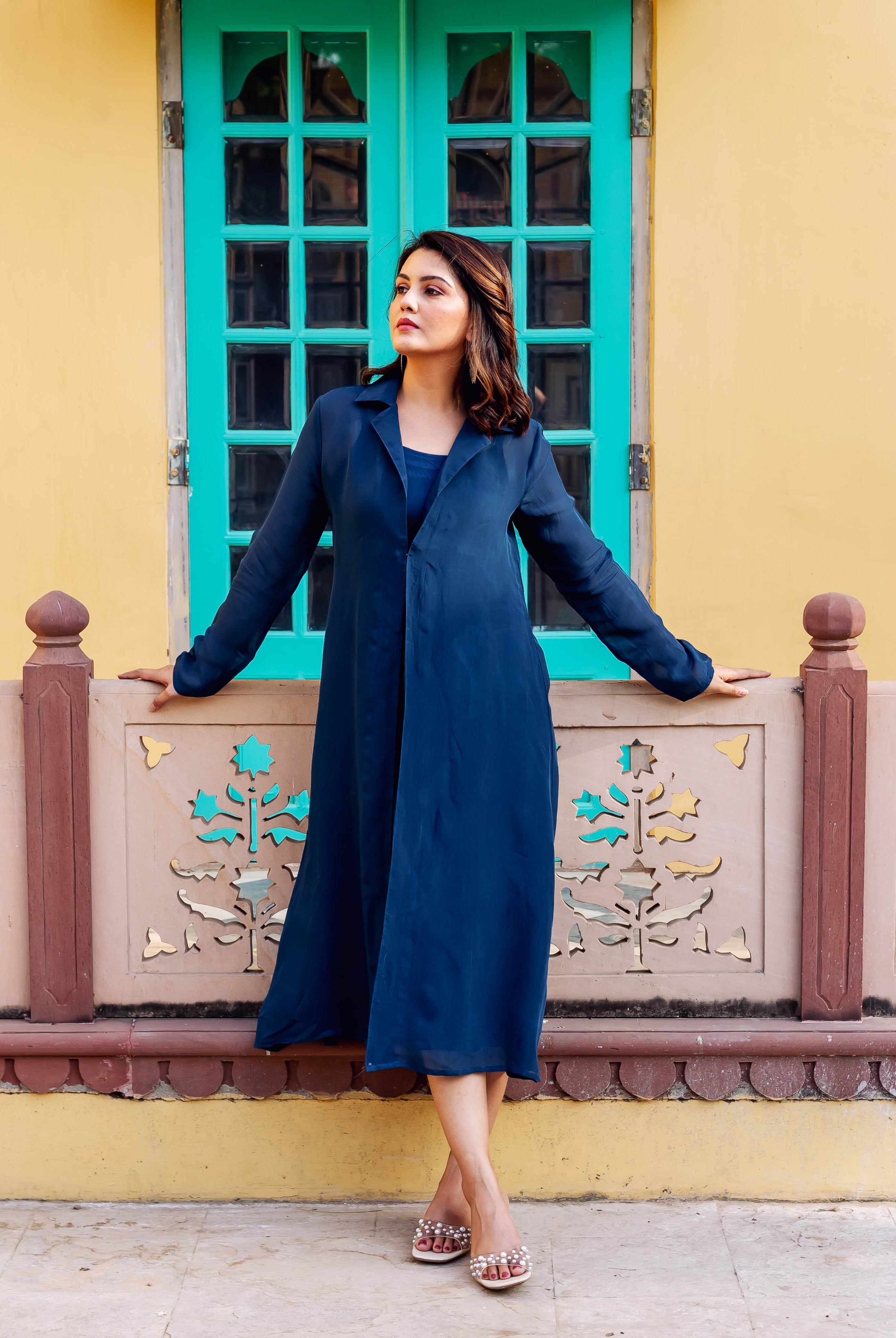 Model wearing a flowing plain twilight blue long coat and dress in an ethnic style.