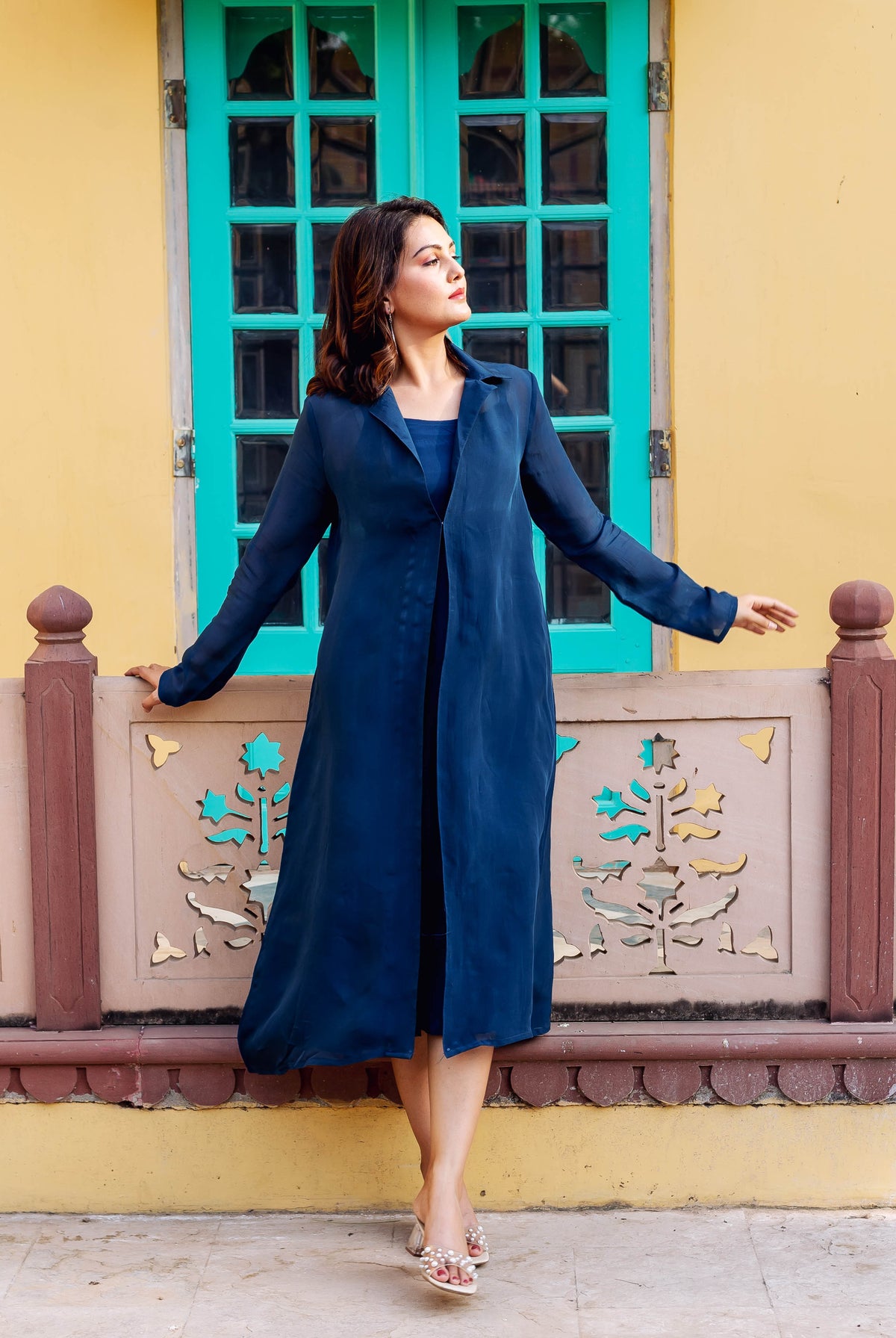 Model in flowing twilight blue ensemble featuring a long open jacket and dress.