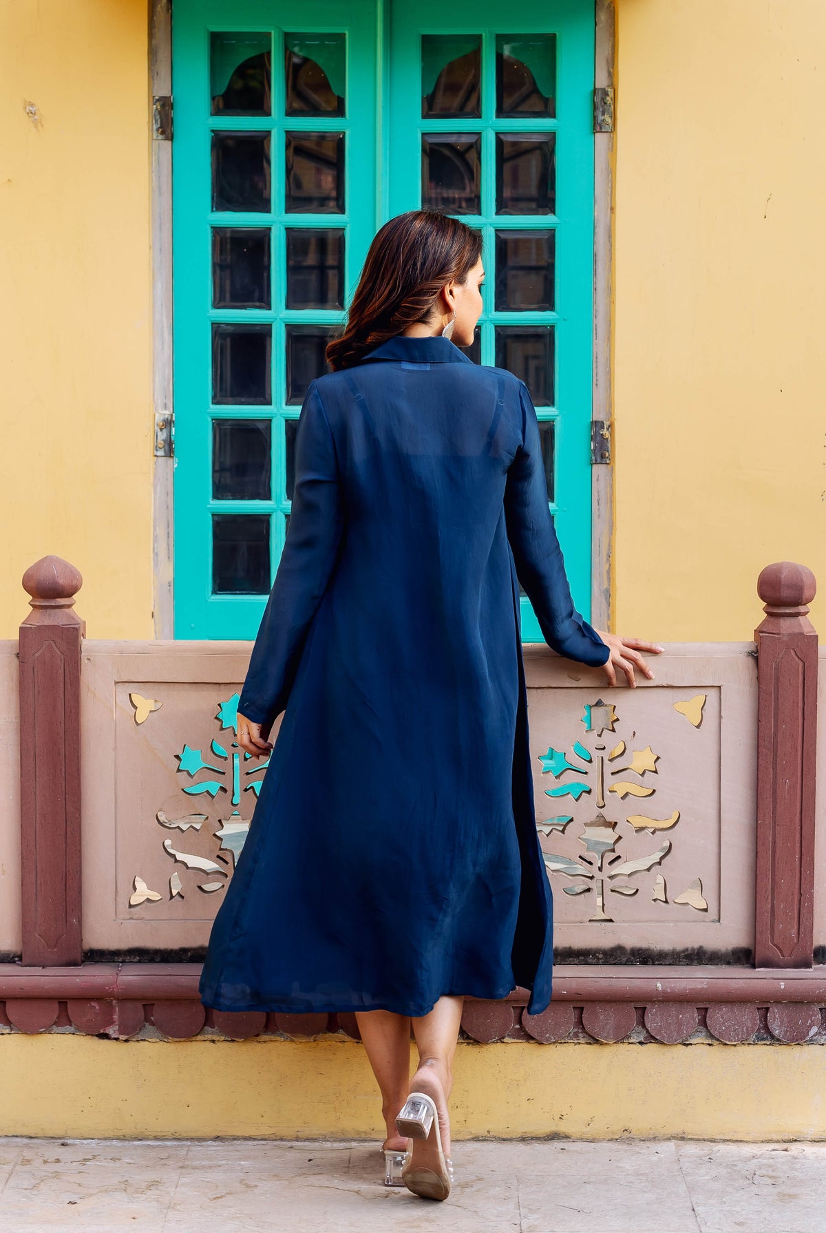 Rear view of a woman in a long, flowing twilight blue ensemble, looking right.