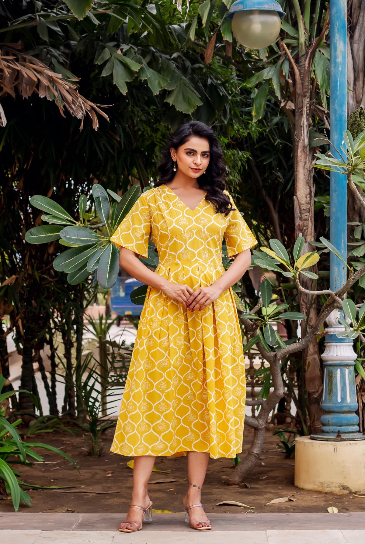 Full shot of a model wearing a mustard yellow hand-block-printed ethnic dress with white trellis pattern.