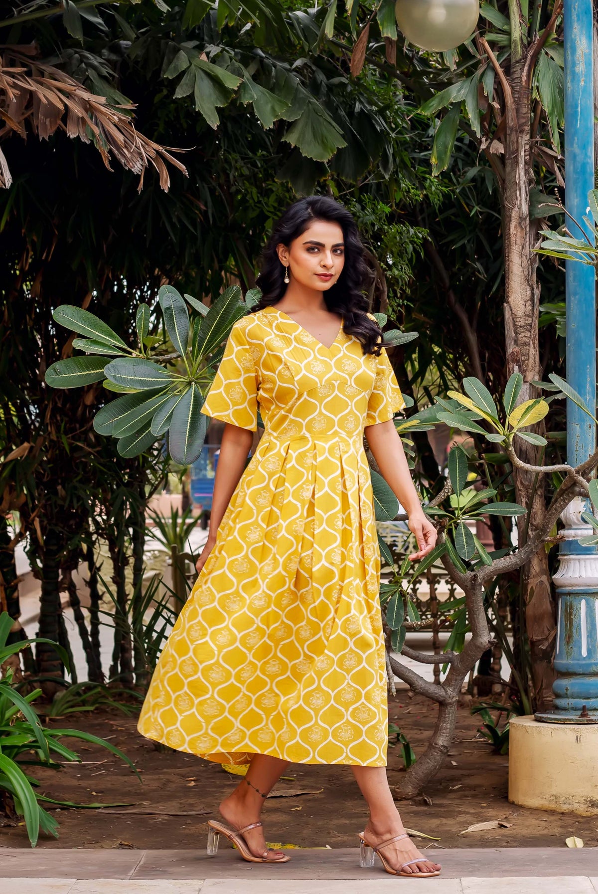 Model in a full-length pleated mustard yellow dress with white hand-block print.