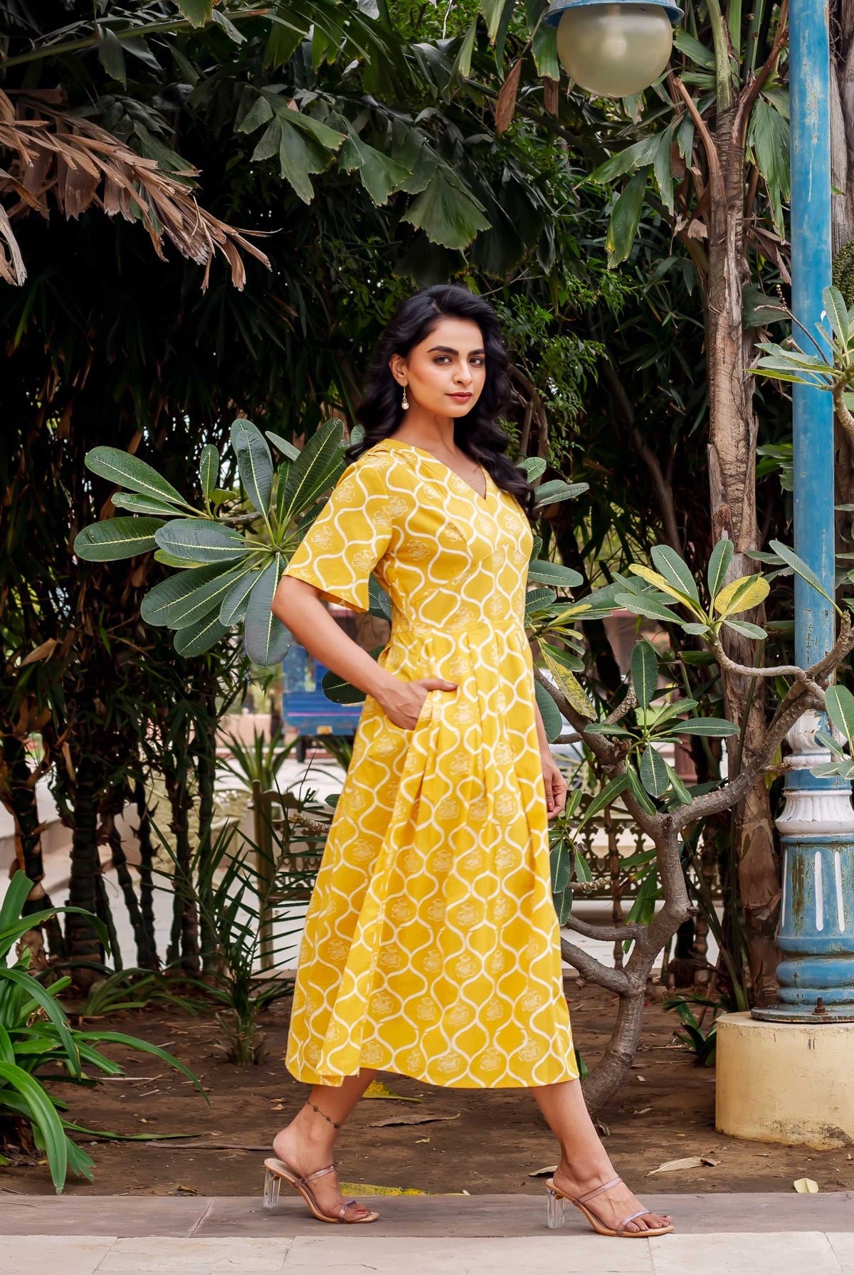 Model in a mustard yellow hand-block printed ethnic midi dress with side pockets, walking.