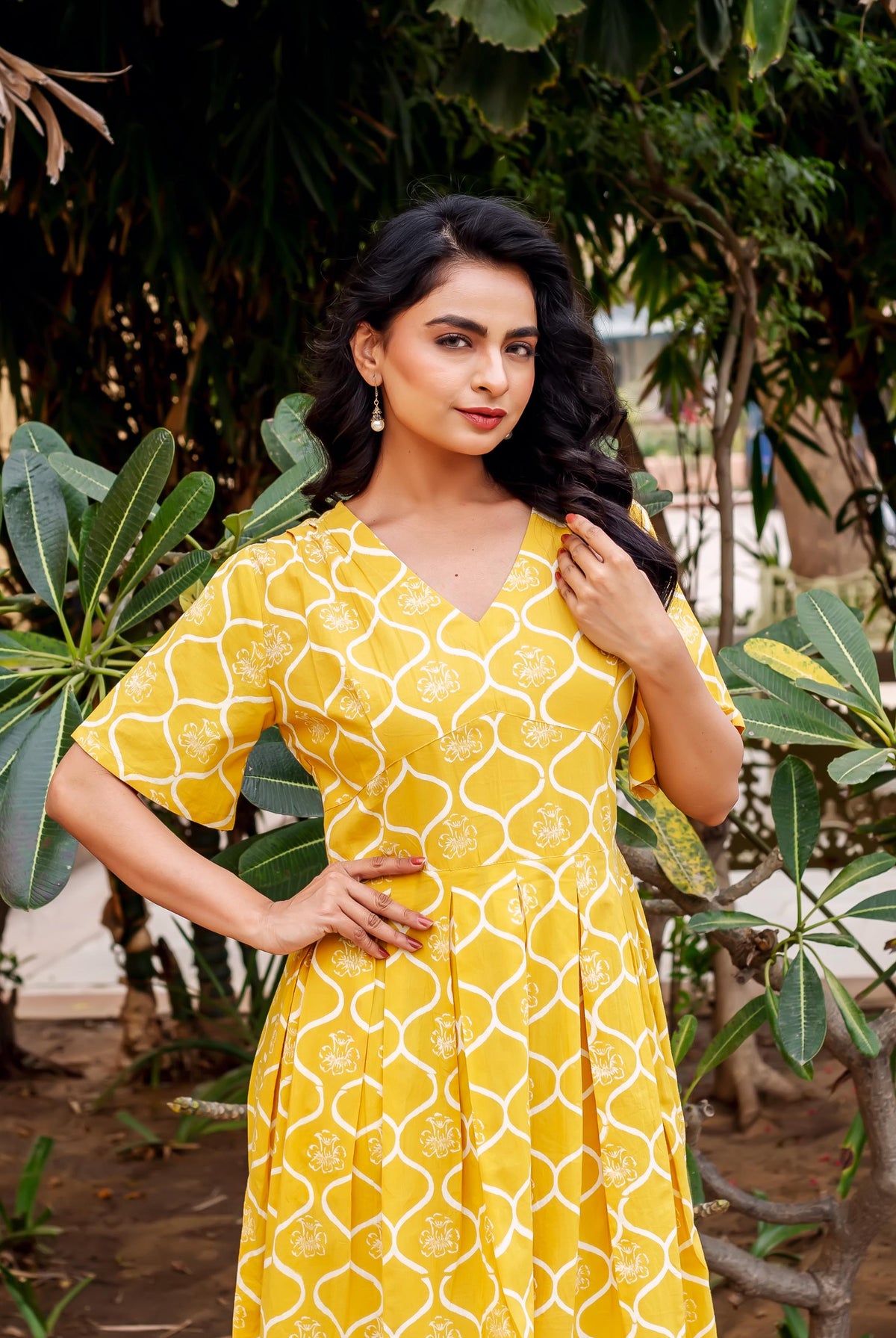 Rhea Mustard Dress, yellow with white Moroccan trellis print, on a woman outdoors.