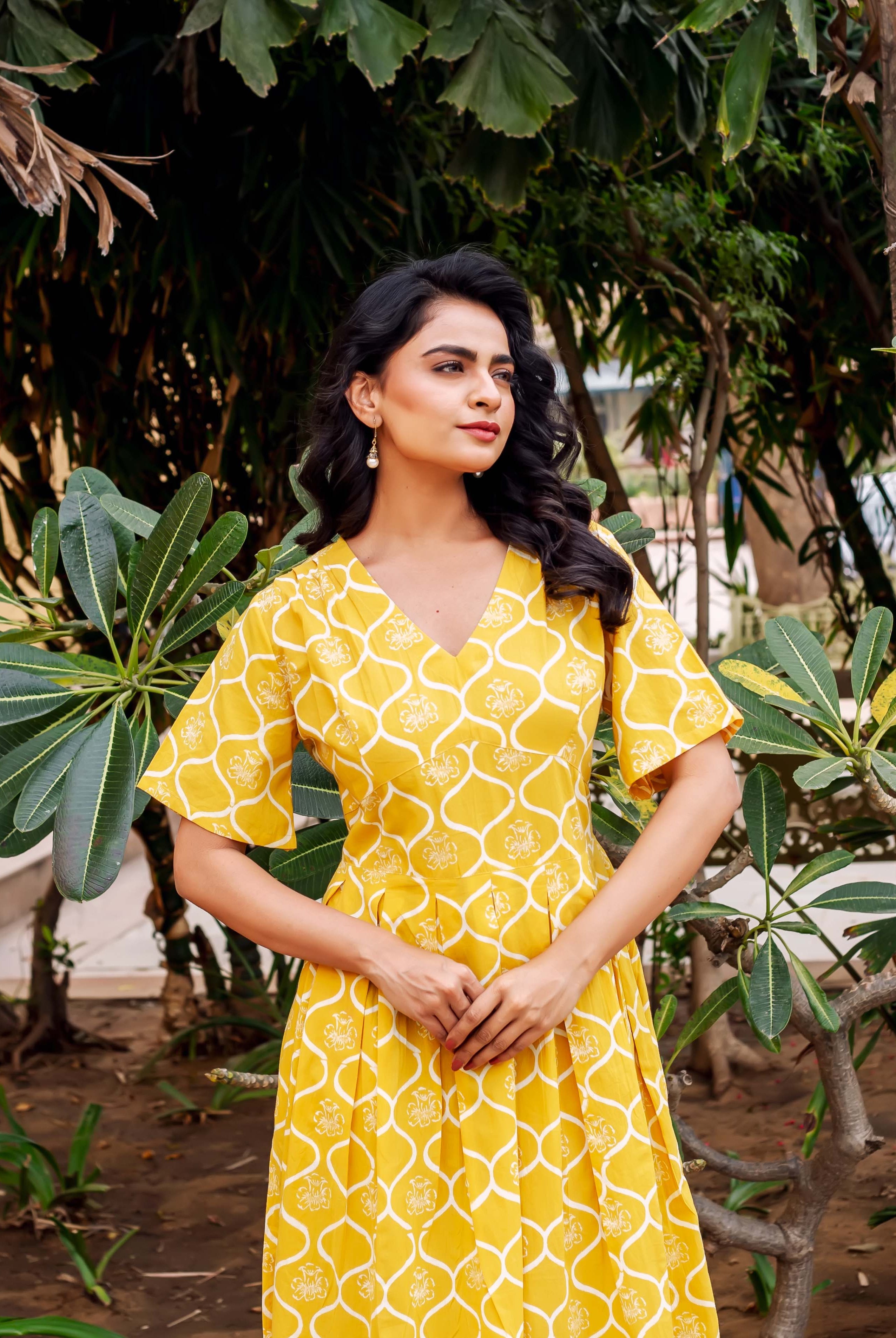 Model wears mustard yellow V-neck ethnic dress with white geometric block print.