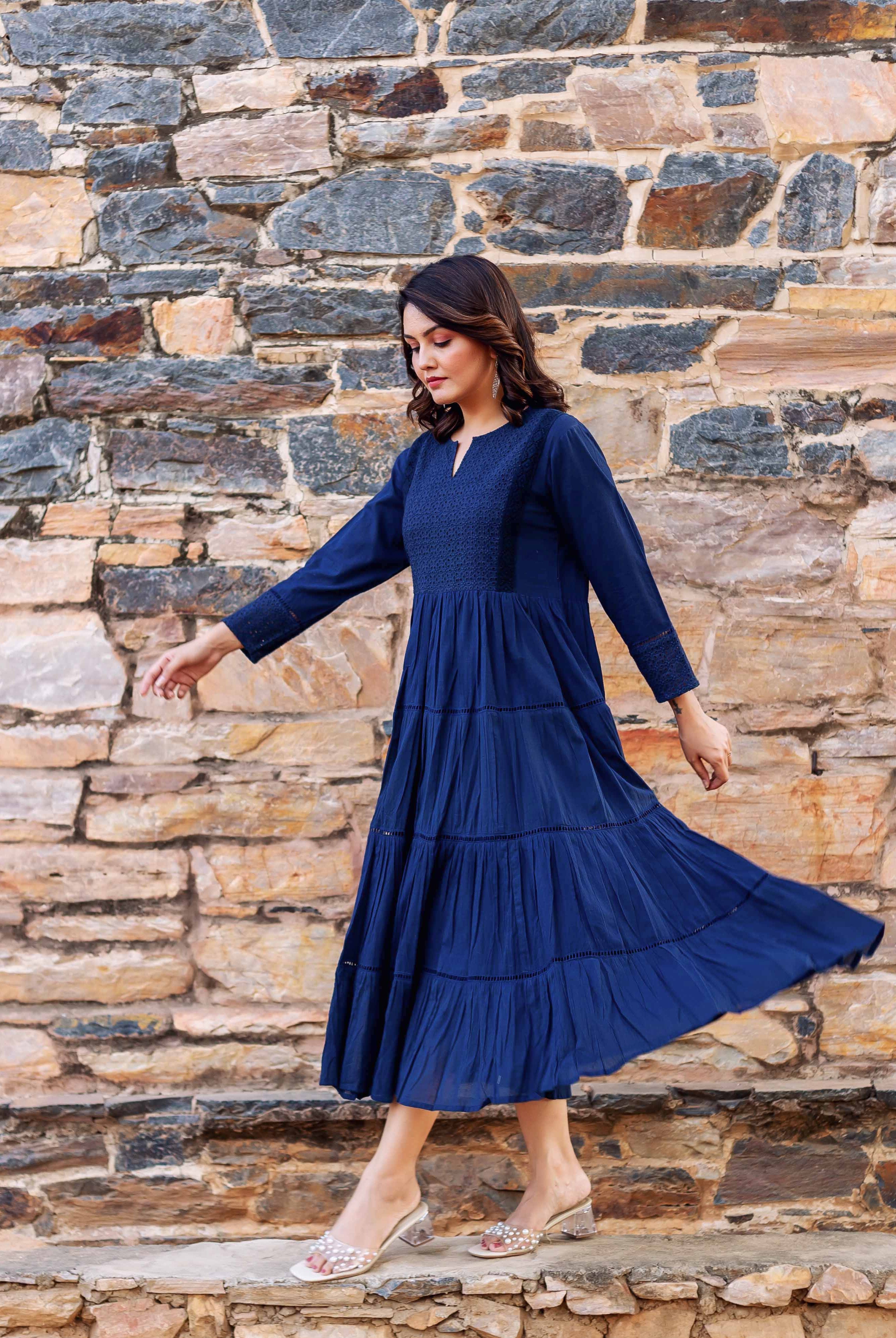 Model in full-length indigo tiered dress featuring patterned yoke and sleeve cuffs.