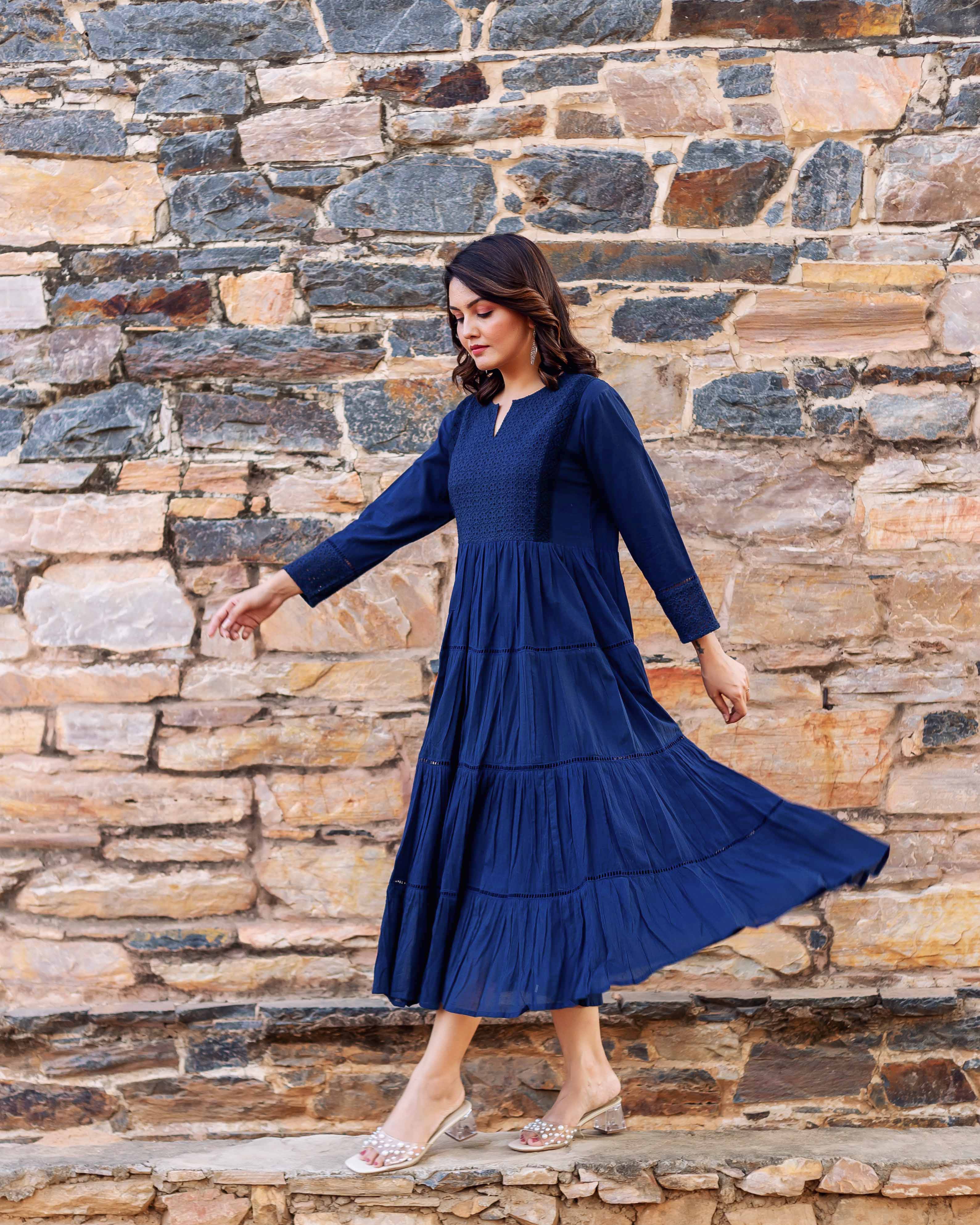 Model in full-length indigo tiered dress featuring patterned yoke and sleeve cuffs.