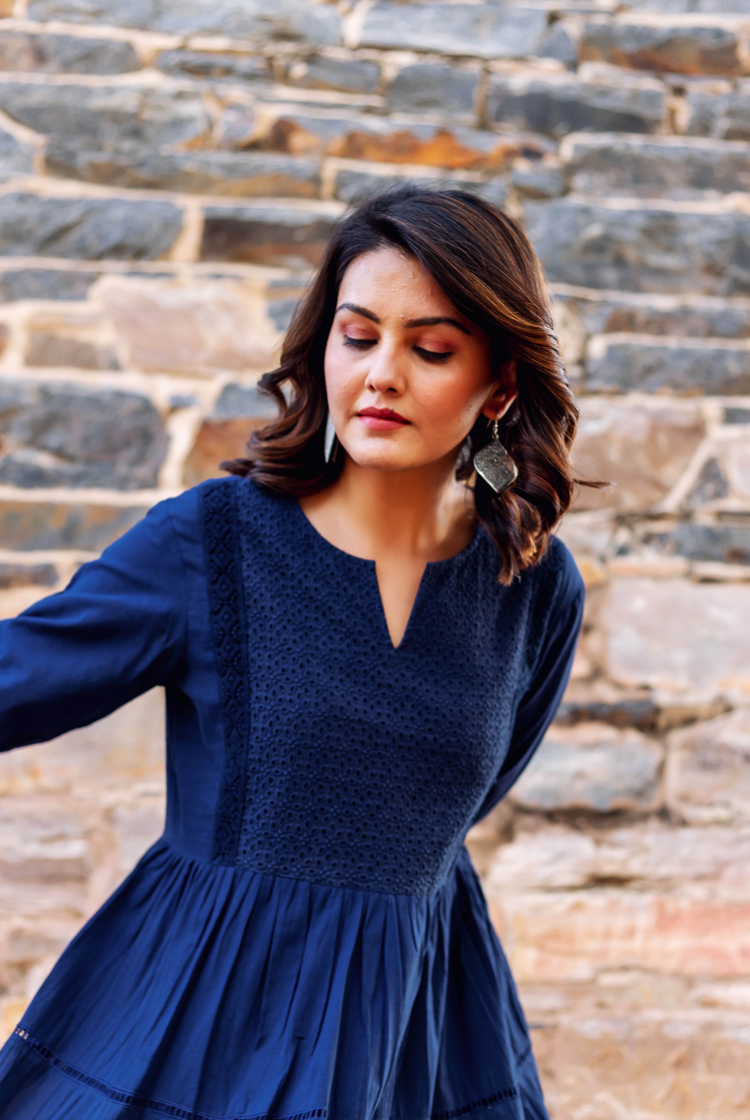Indigo blue tiered dress on model, with embroidered yoke, V-neck, and long sleeves.