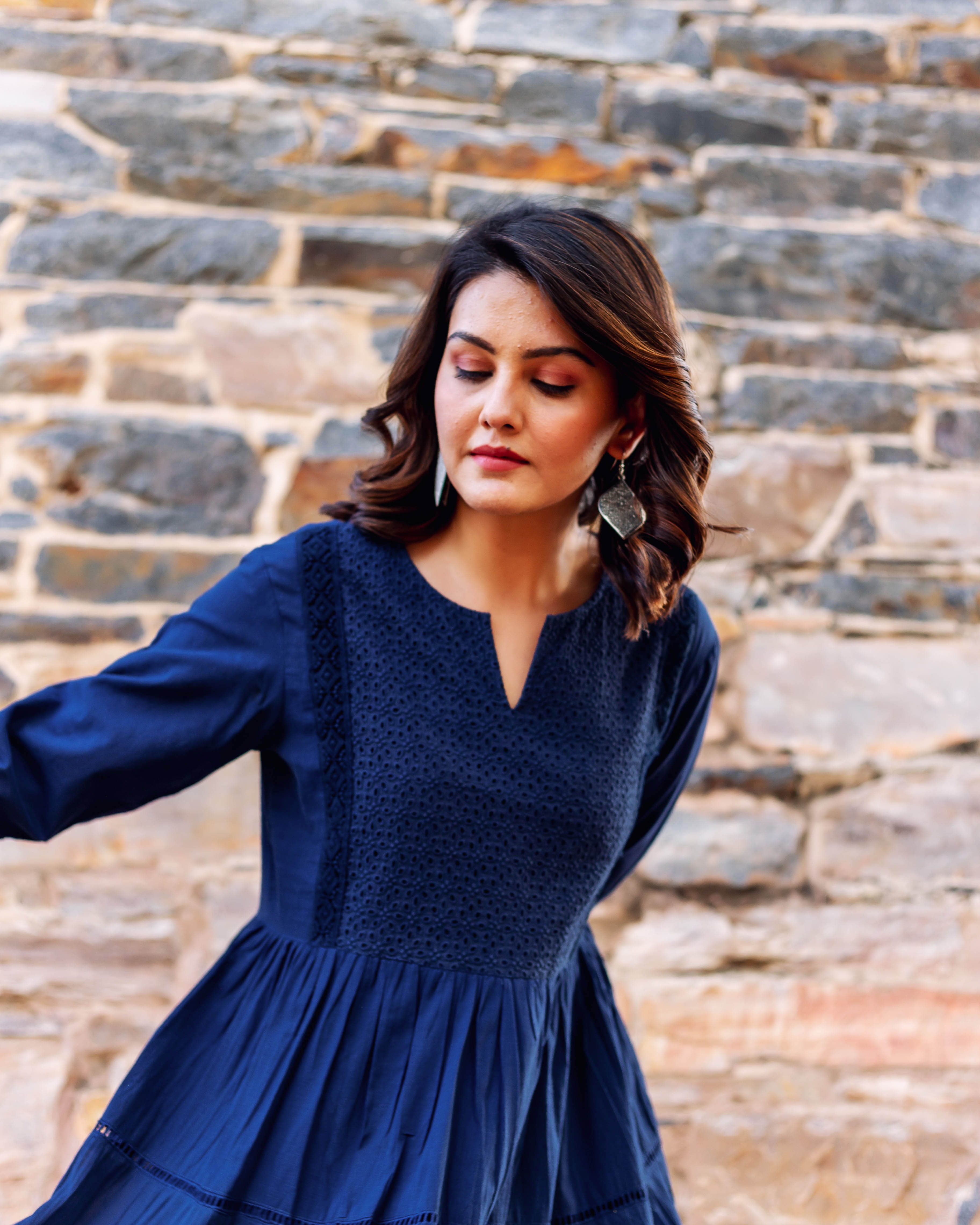 Indigo blue tiered dress on model, with embroidered yoke, V-neck, and long sleeves.