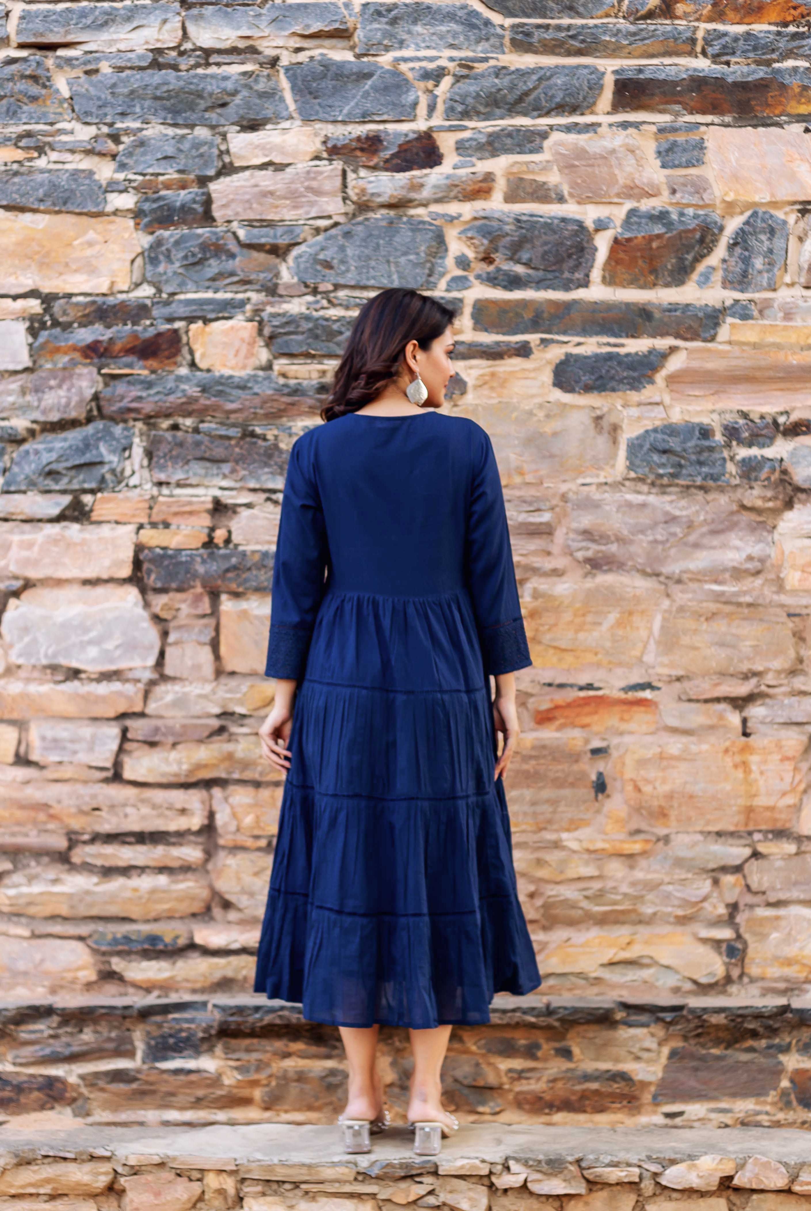 Woman from back wearing full indigo tiered midi dress with embroidered sleeves.