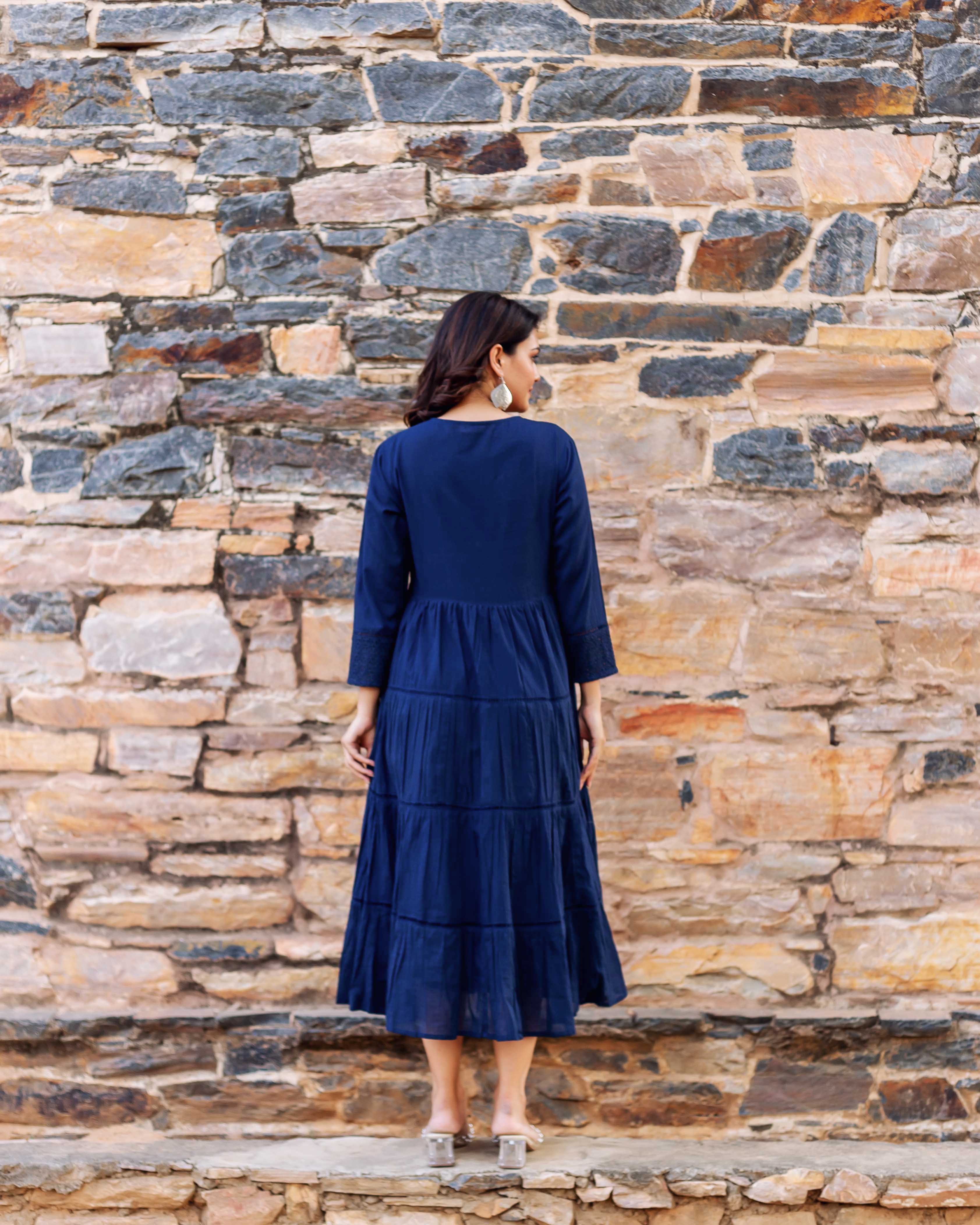 Woman from back wearing full indigo tiered midi dress with embroidered sleeves.