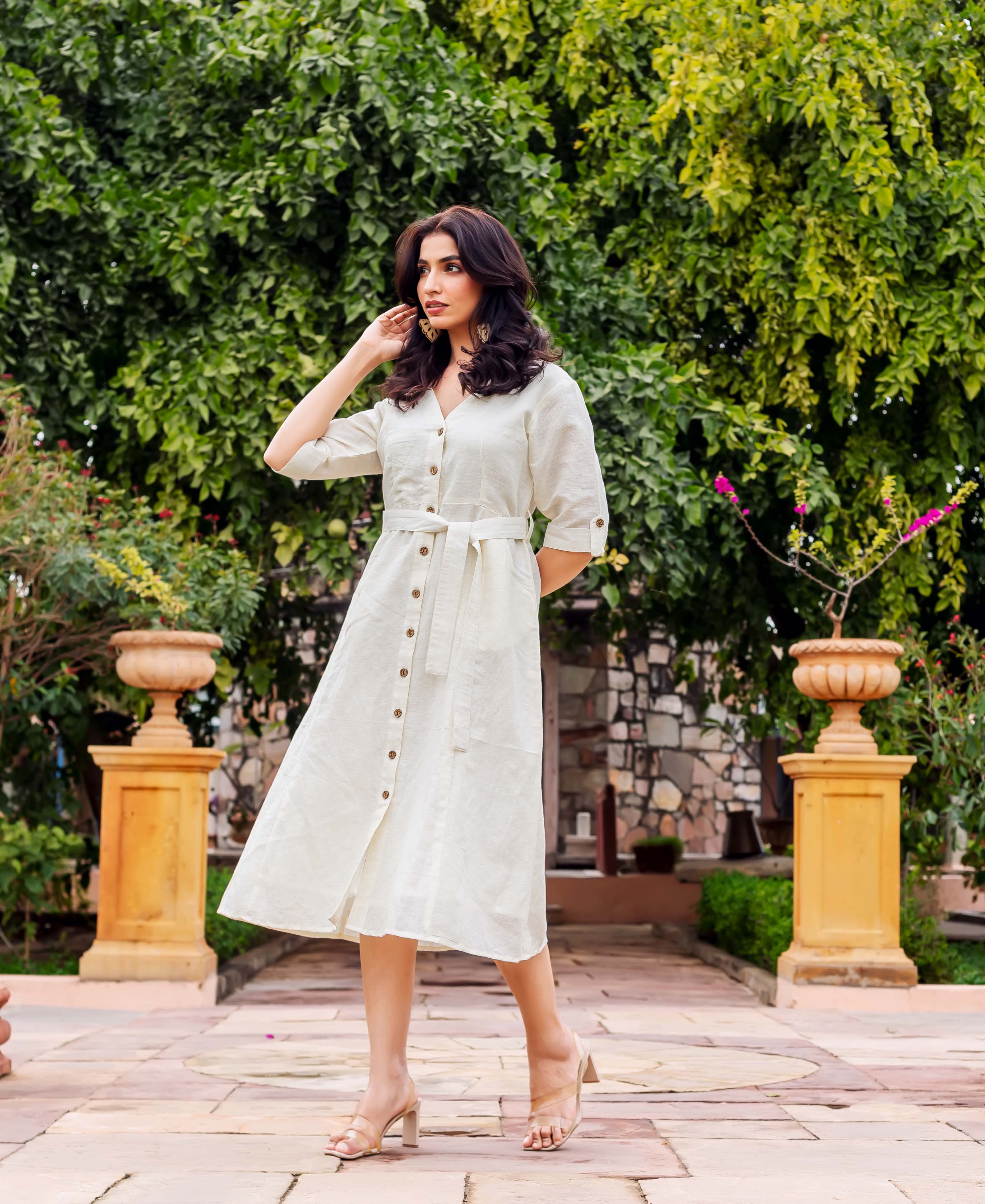 A woman models an off-white button-front belted linen midi dress with 3/4 sleeves.