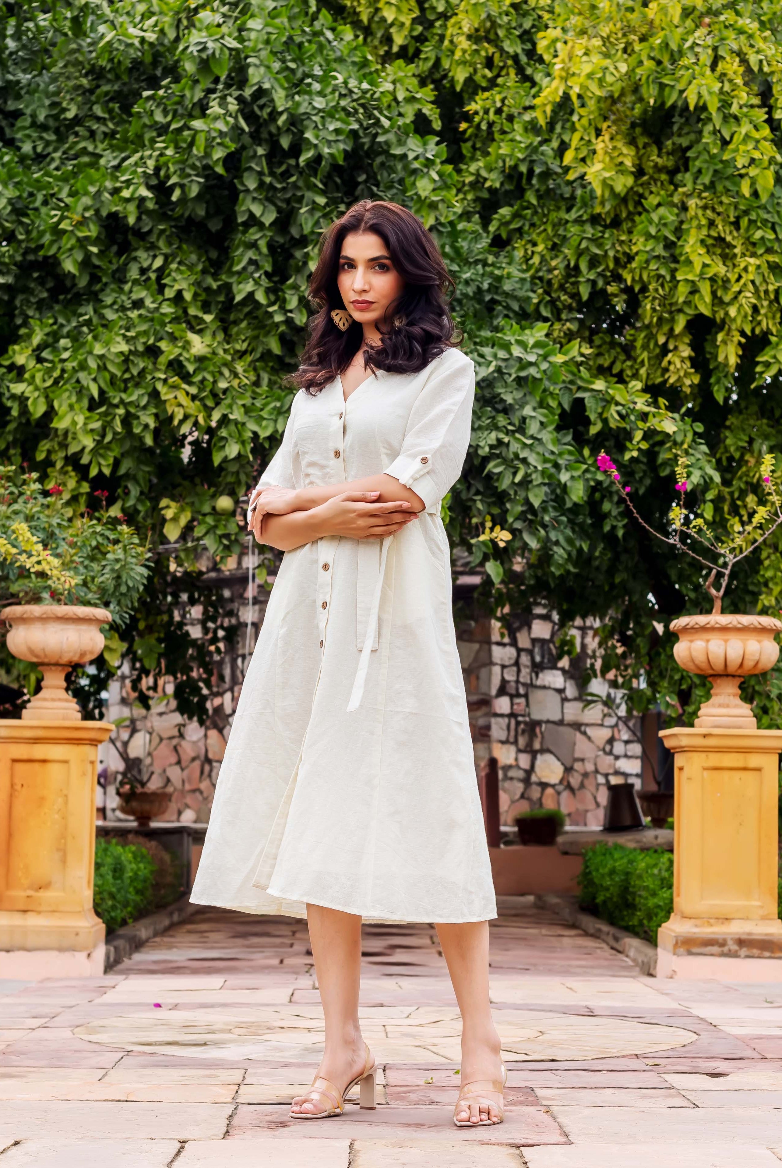 Model wearing an off-white V-neck button-front A-line midi dress with tie-waist.