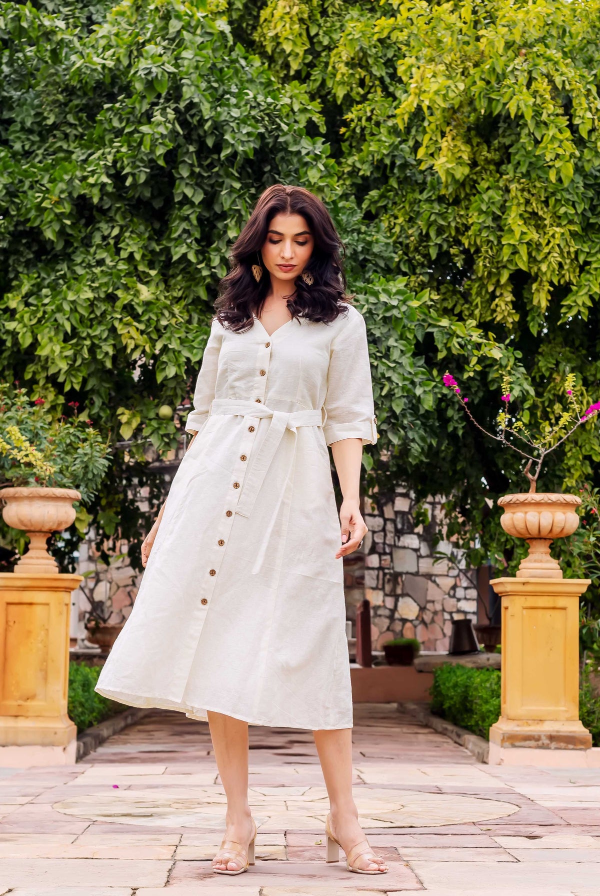 Model in off-white linen midi dress, V-neck, belted waist, and button-down front.