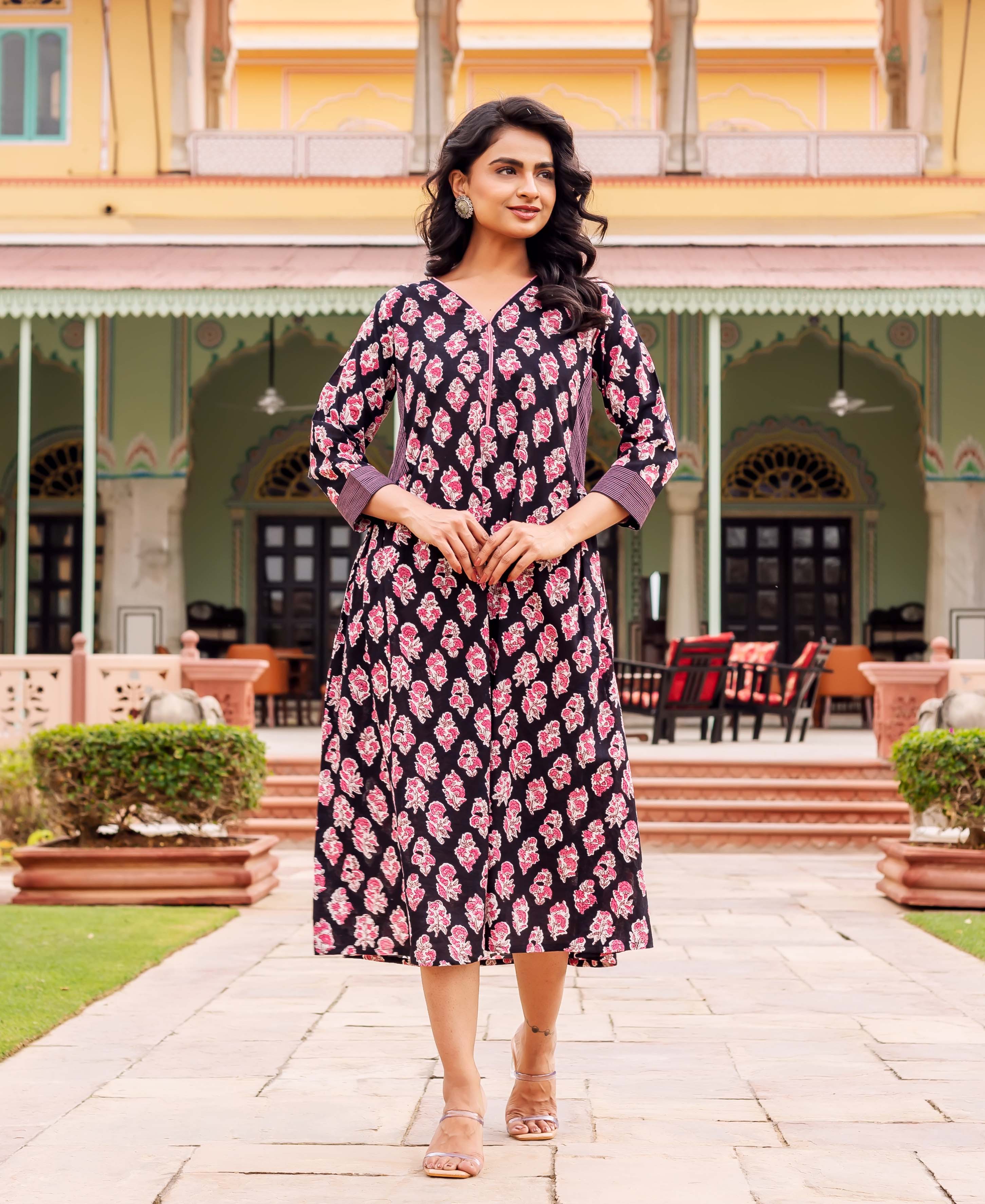 Woman in a black V-neck midi dress with pink hand-block-printed floral patterns.