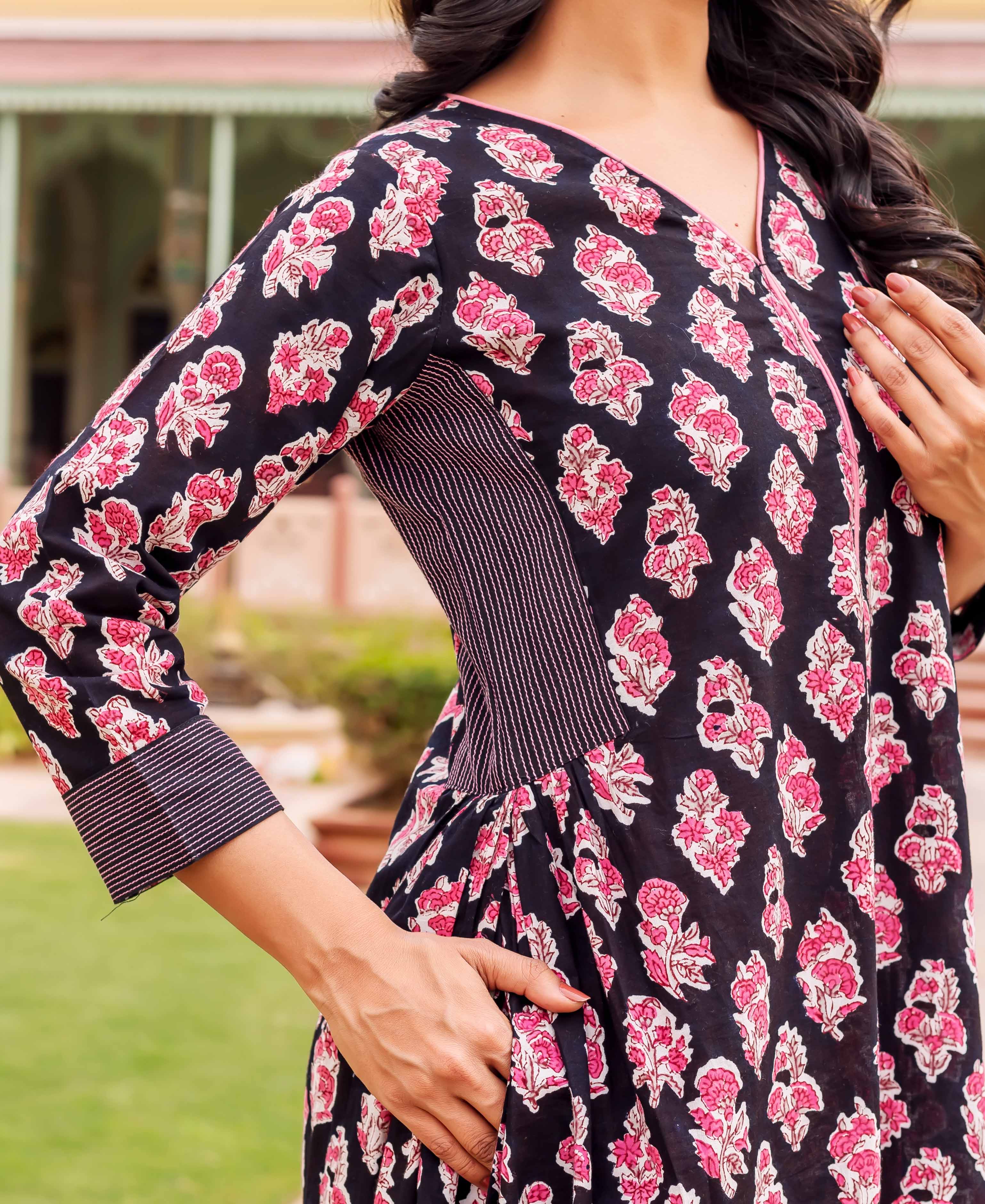 A model wears a black, pink, and white floral print dress with a V-neckline.