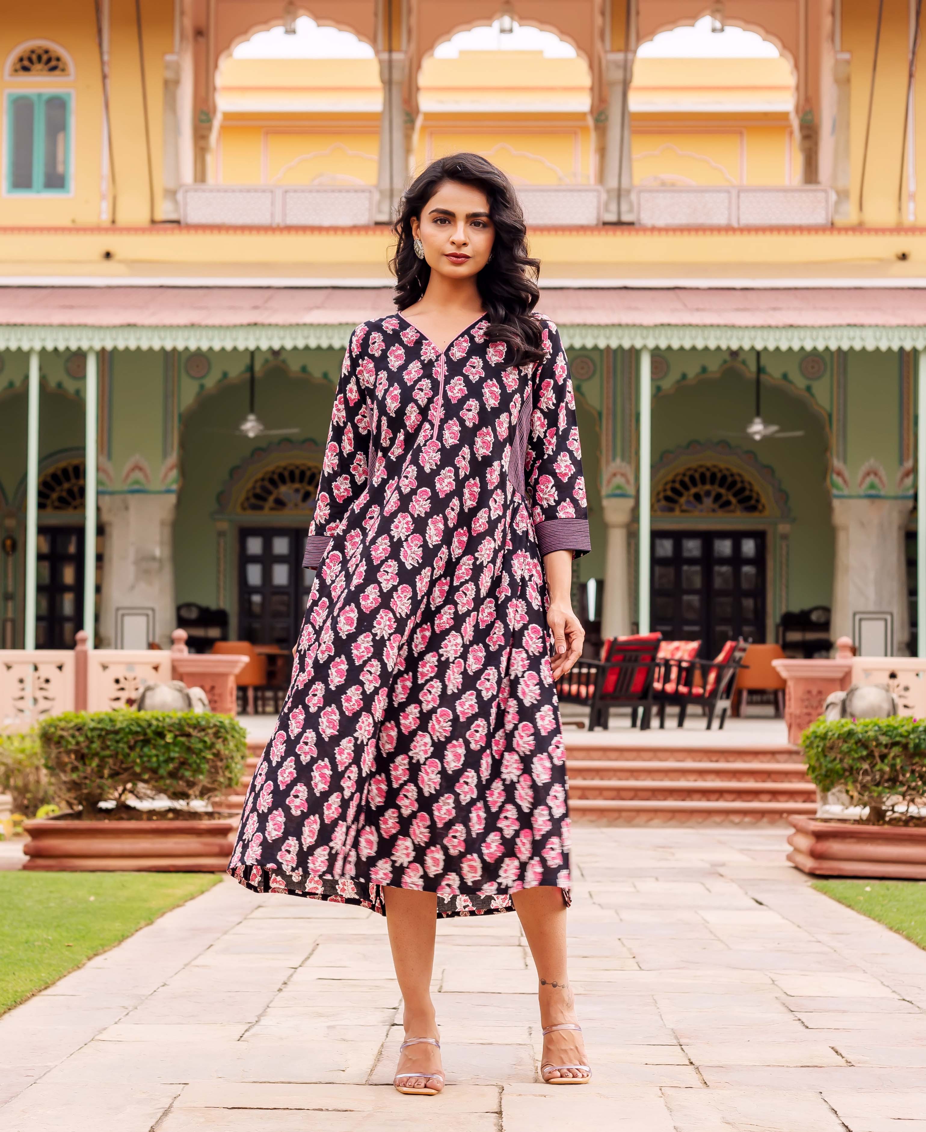 Full shot of model wearing a black cotton dress with pink hand-block floral prints.