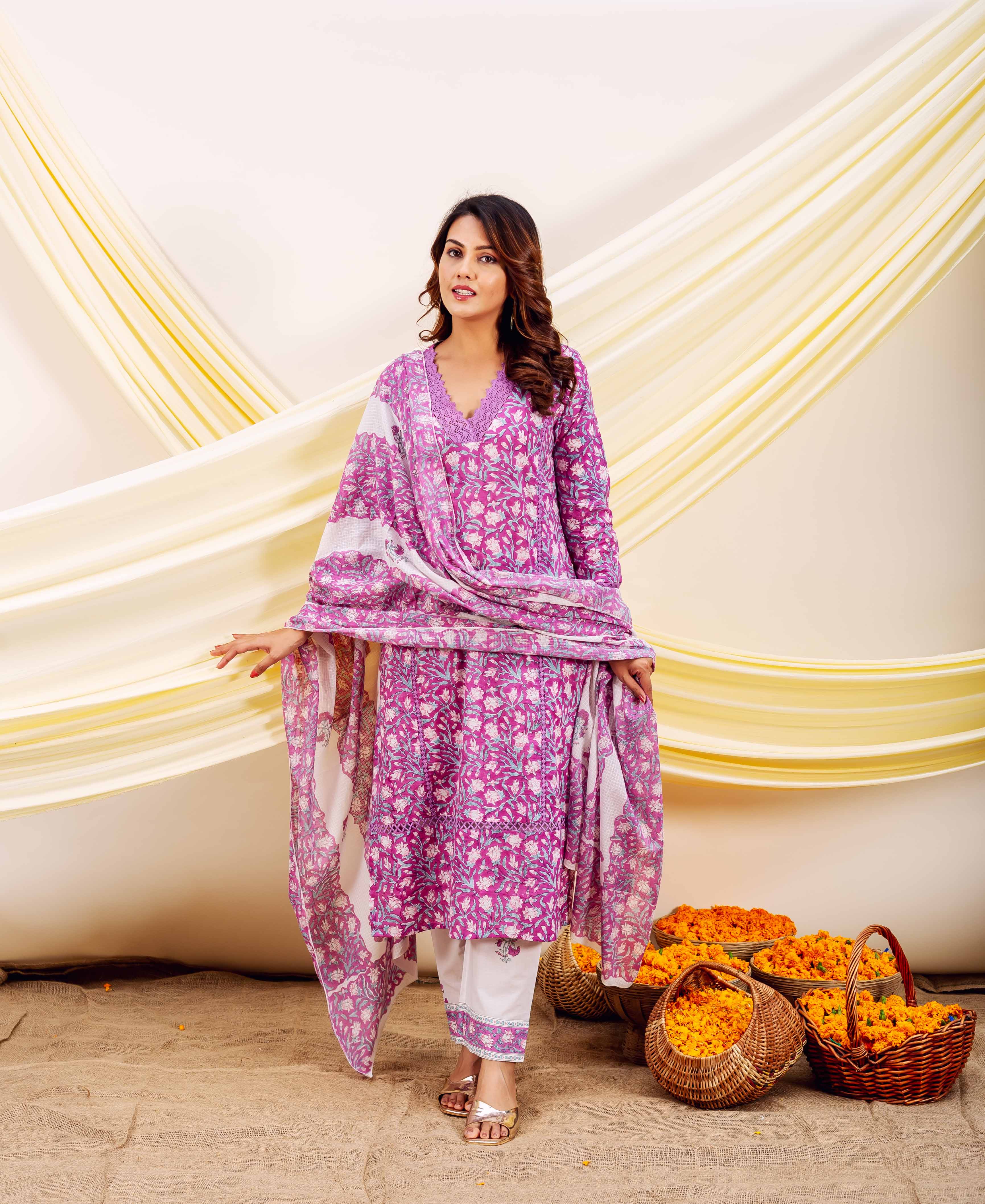 Full-length photo of a woman in a purple and white hand-block printed floral ethnic ensemble.