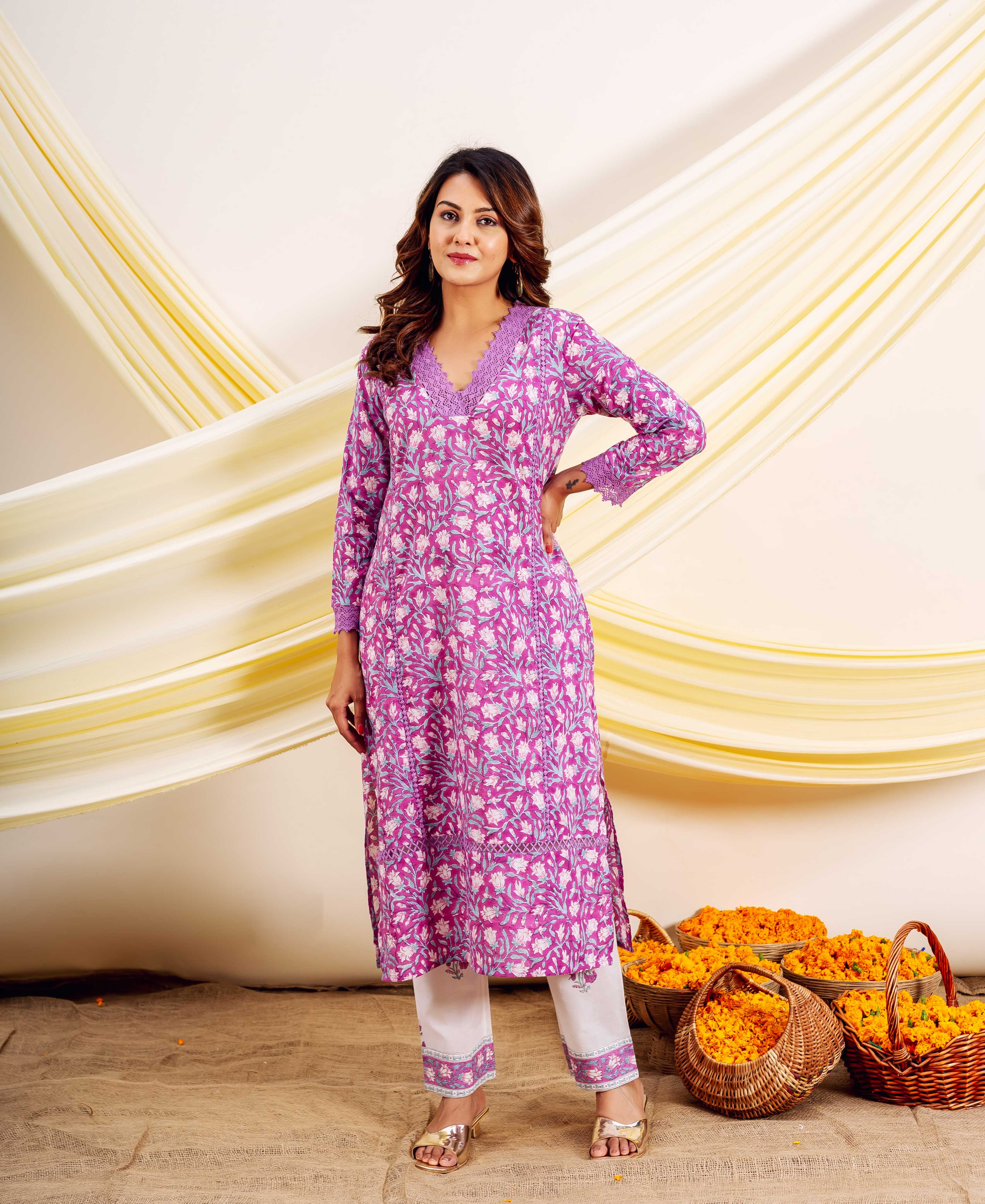 Woman wearing a purple hand-block-printed floral cotton kurta and white pants.