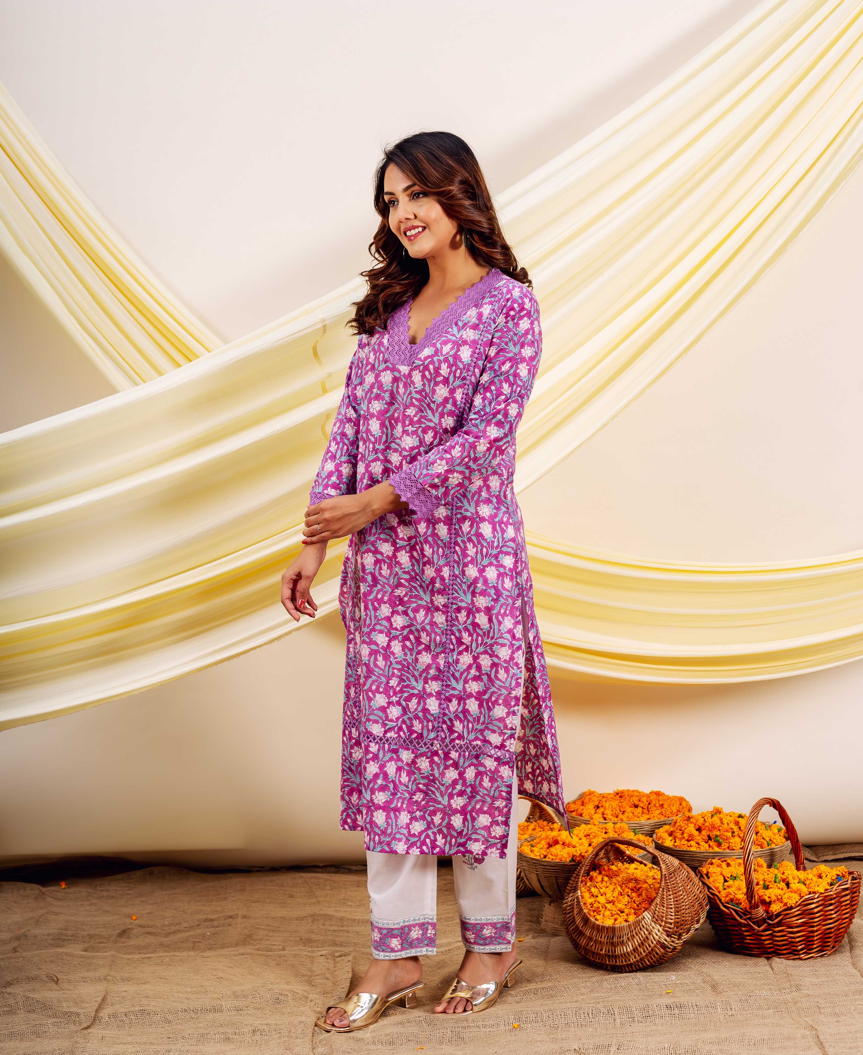 Smiling woman in a vibrant purple hand-block-printed floral cotton kurta and white pants.