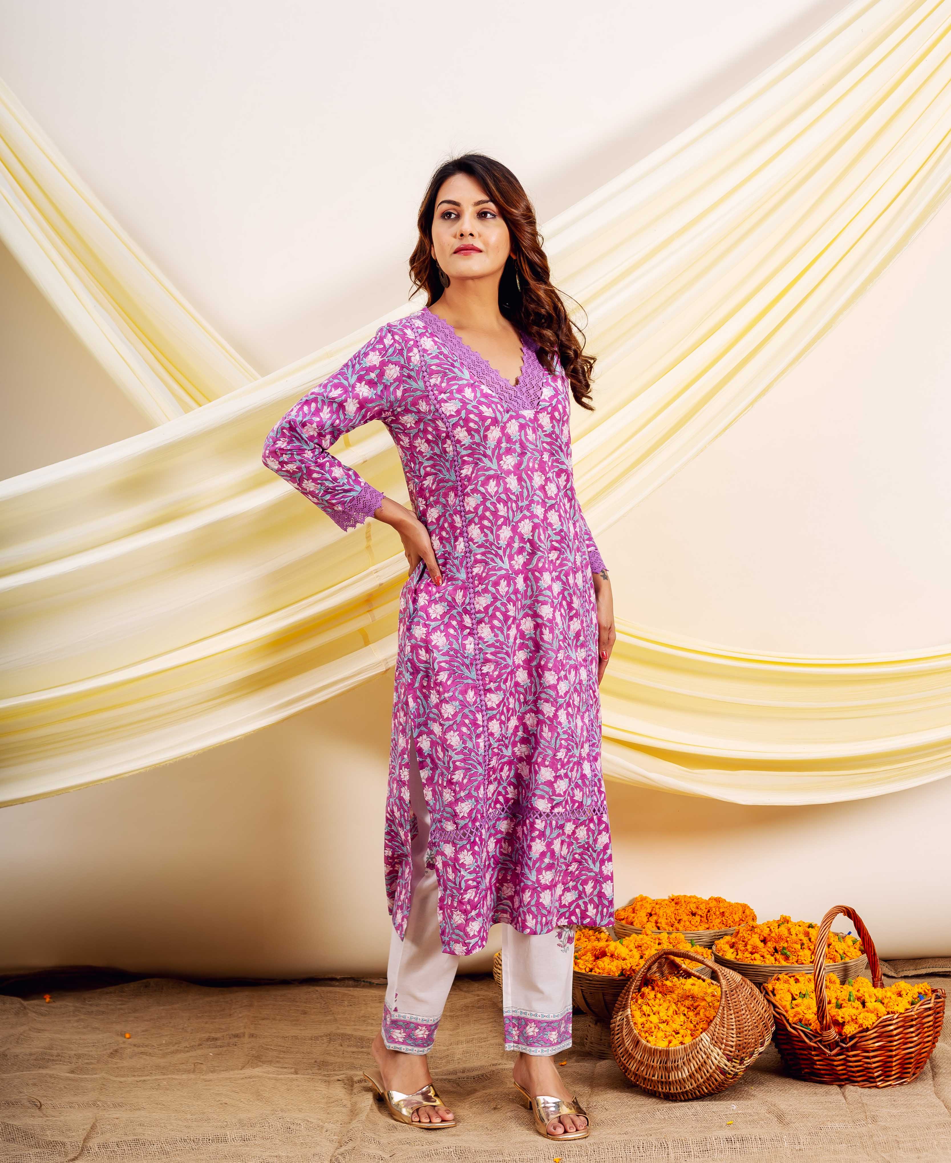A woman models a pink and white floral print kurta with white pants.