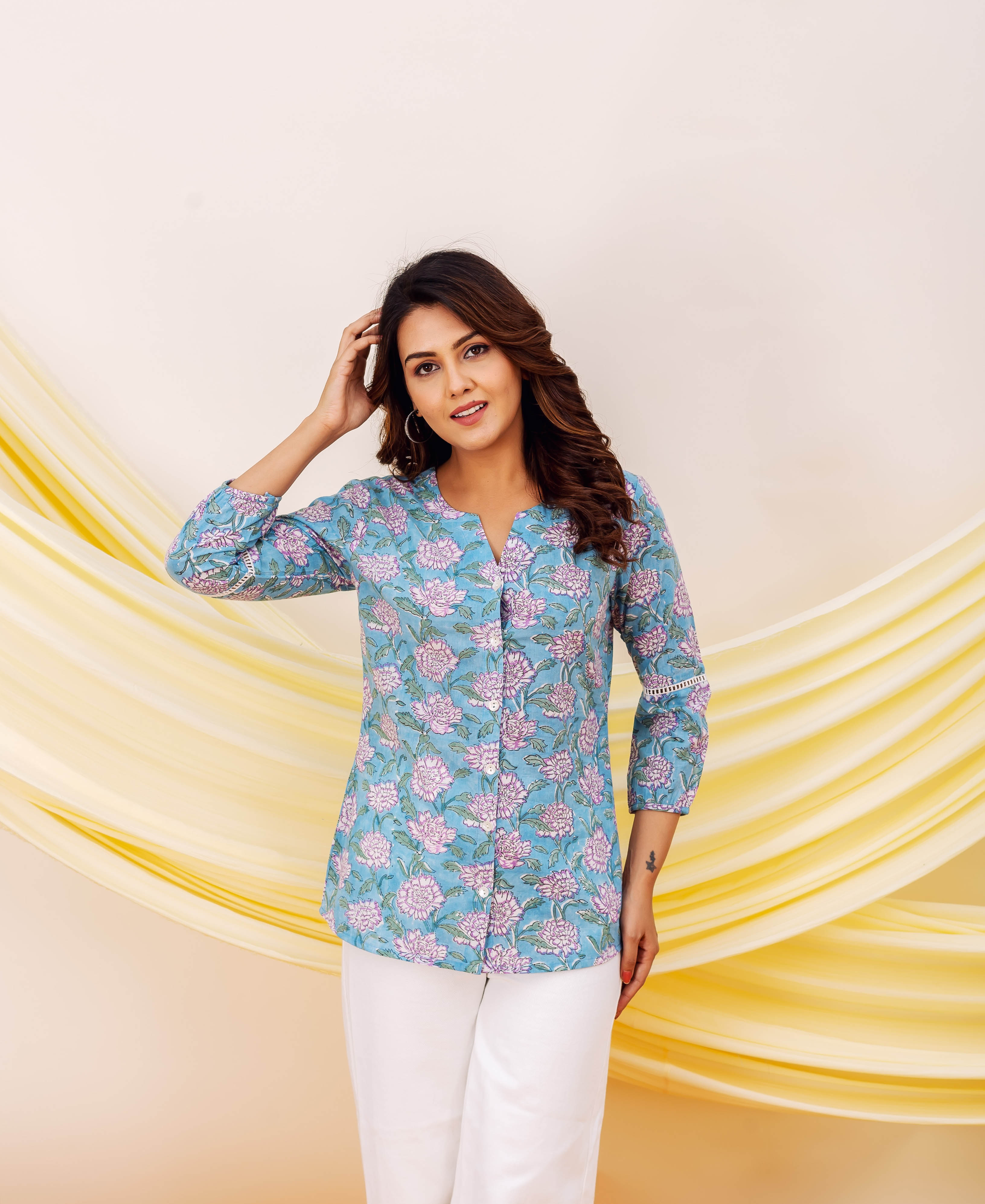 Model in a blue hand-block-printed top, featuring vibrant pink and purple floral print.