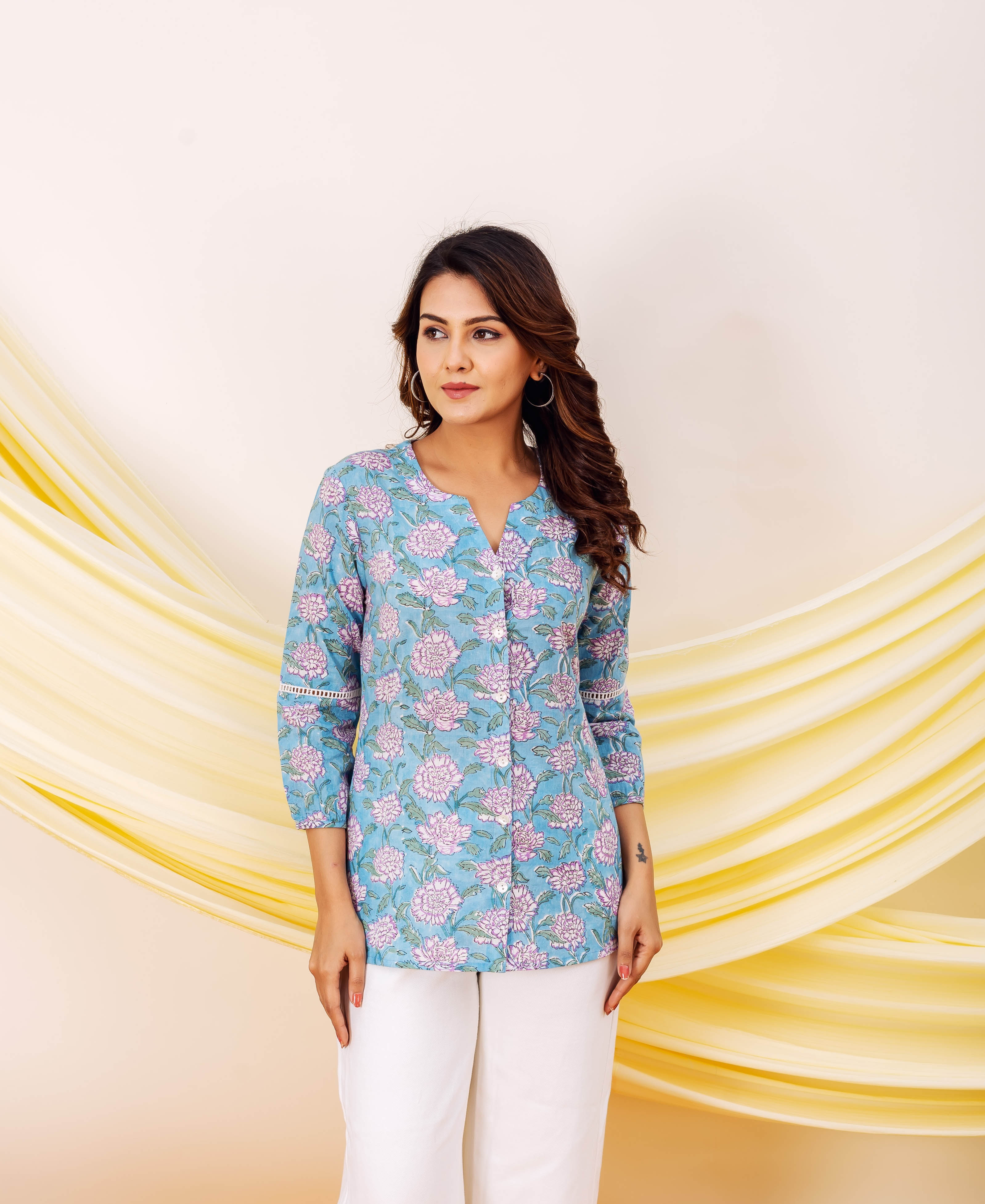 Model wears a light blue multicolour floral printed top with white pants.