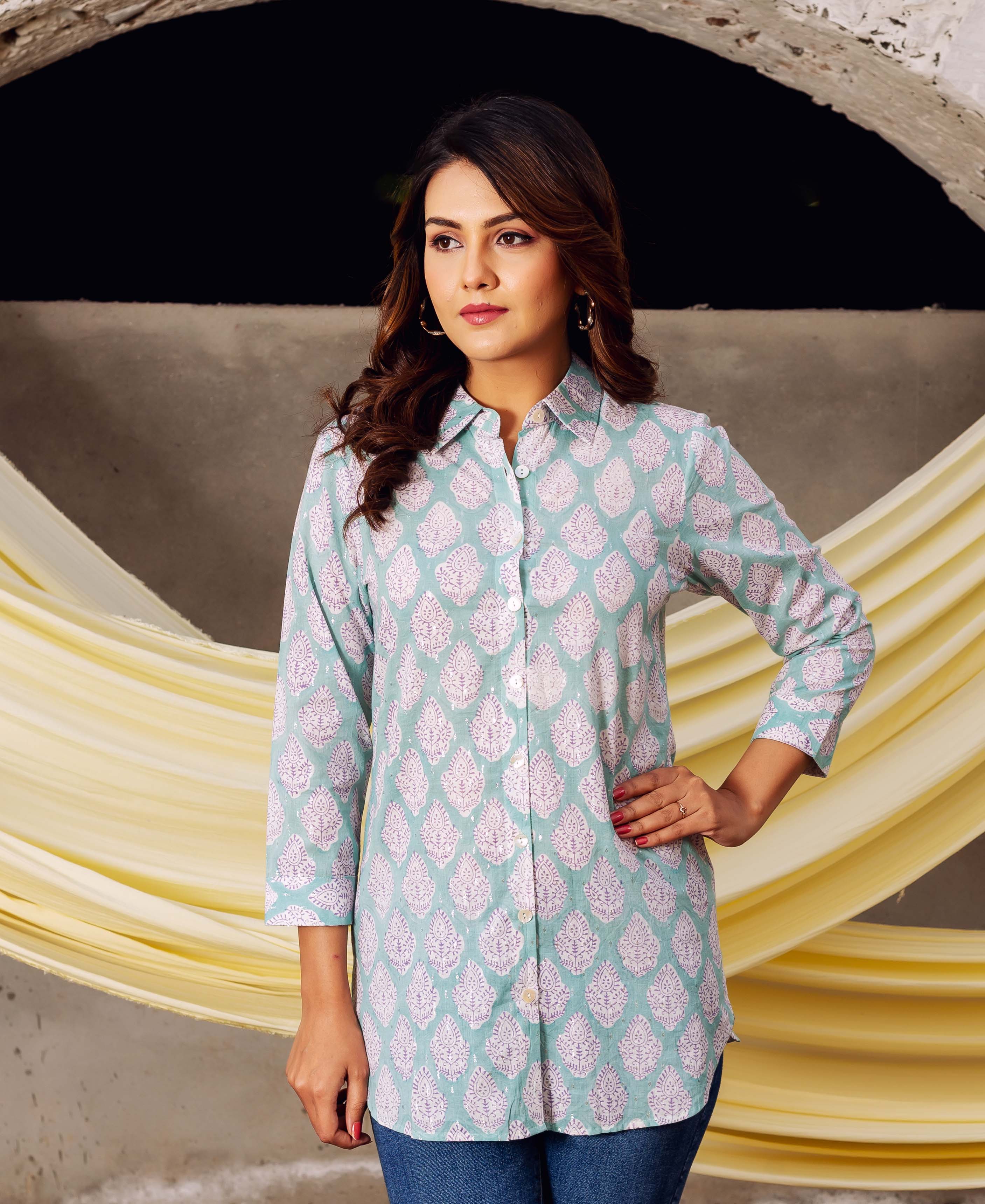 Model wearing a light aqua block printed tunic shirt with white ethnic leaf patterns.