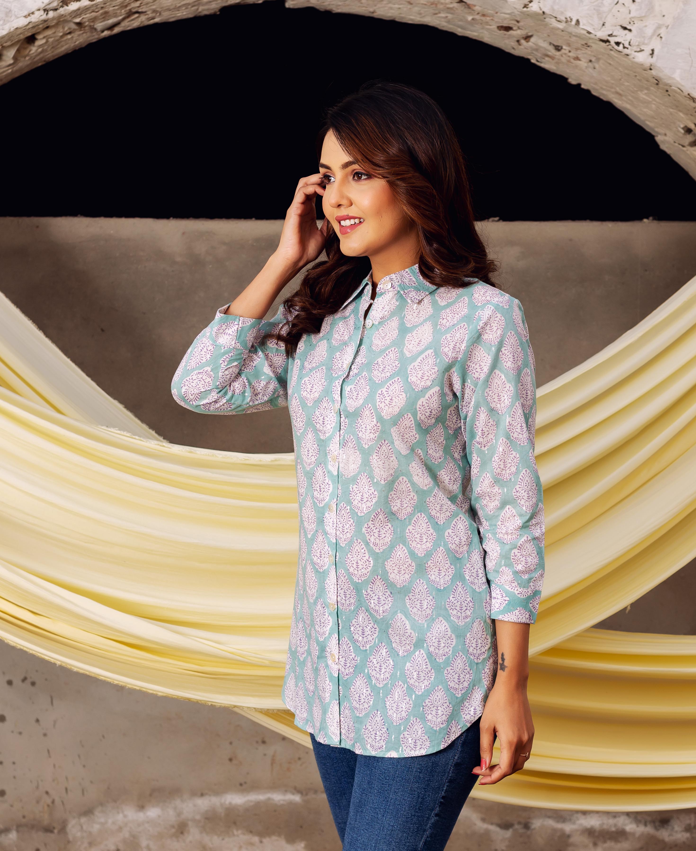 Smiling model in an aqua block-printed collared top featuring white leaf patterns, looking right.
