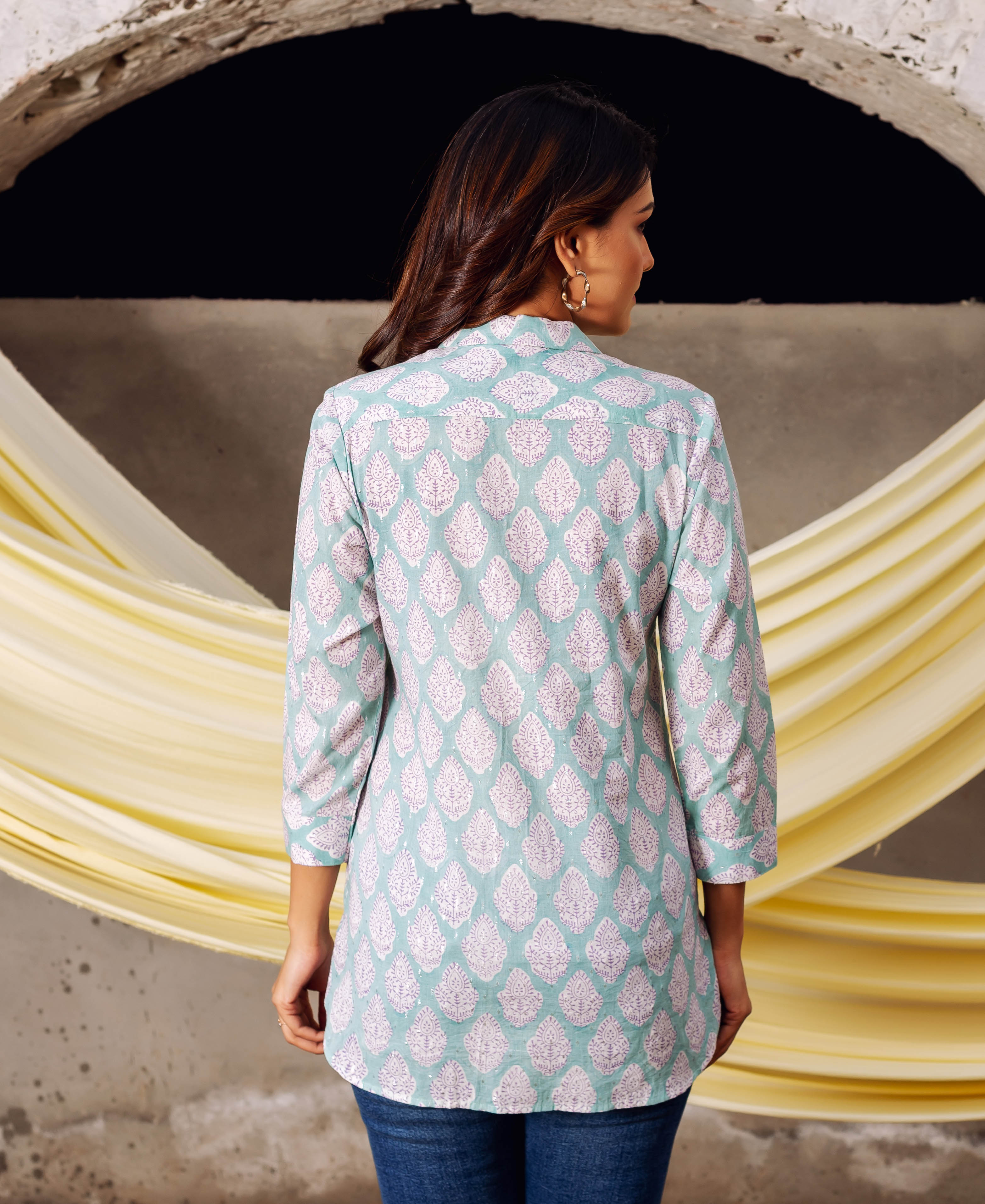 Rear view of a woman in an aqua block-printed top with pink and white traditional motifs.