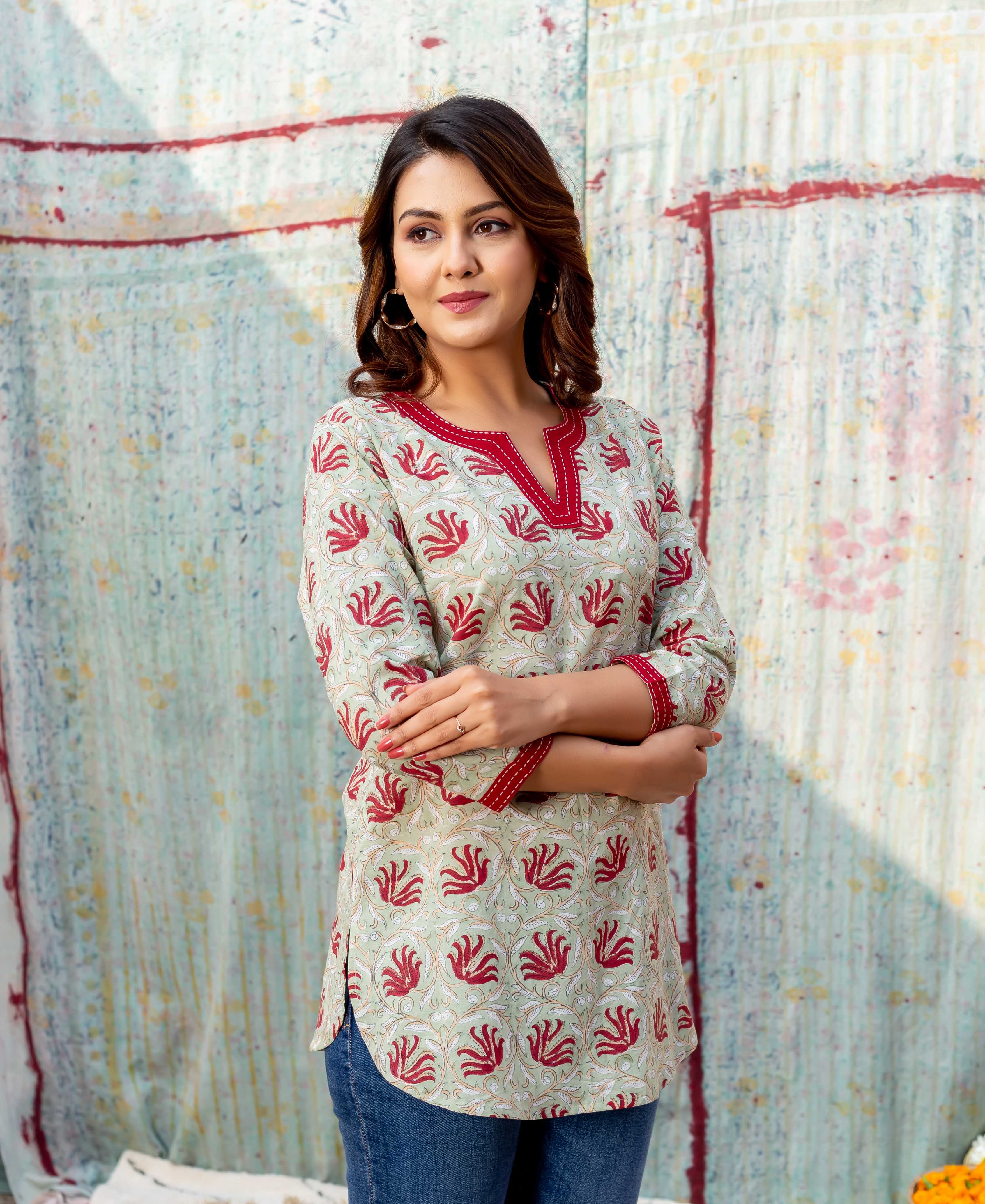 Model wearing a meadow green block-printed top with red floral design and V-neck.