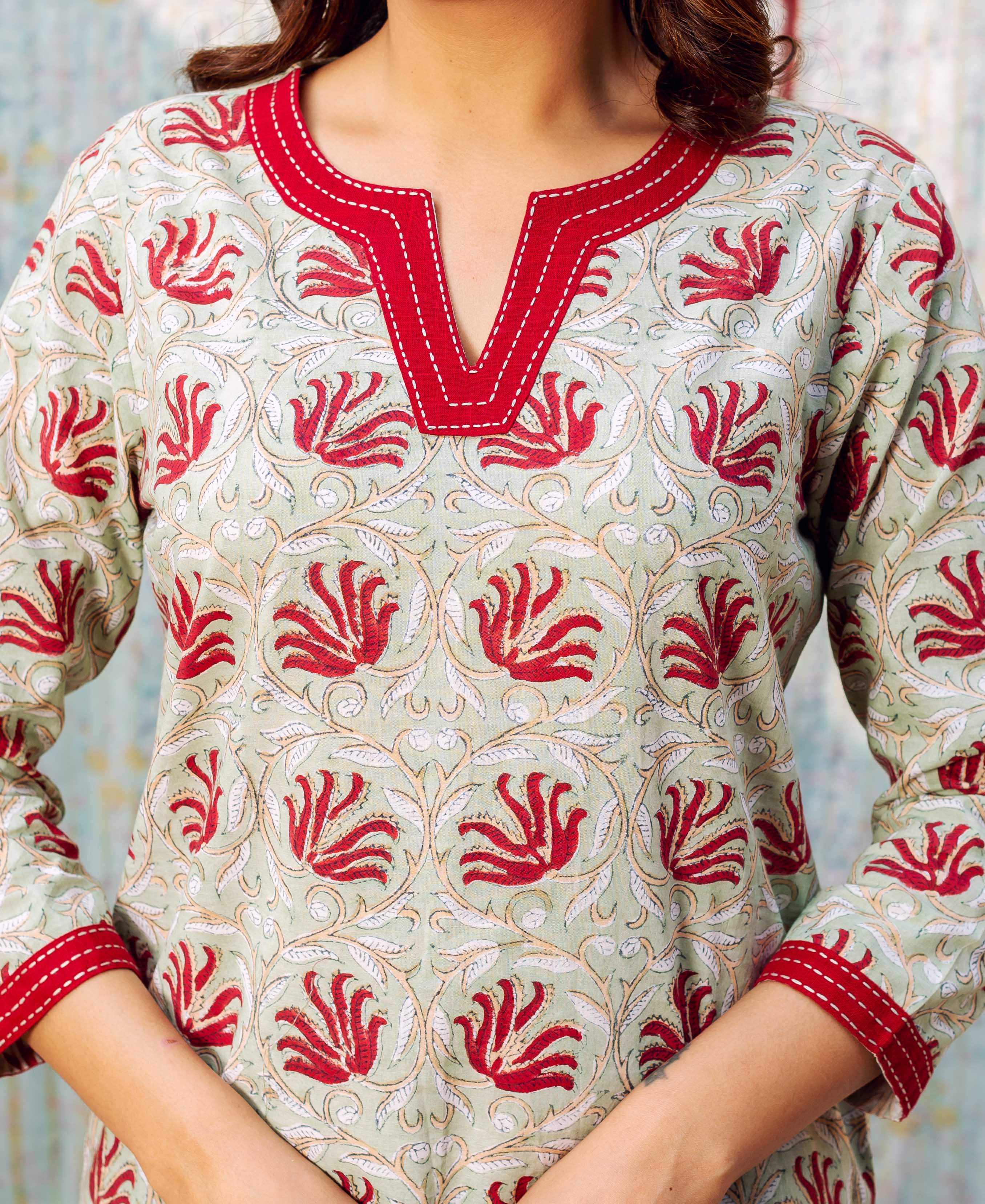 Meadow green block printed top, red floral-leaf pattern, red trimmed V-neck on model.