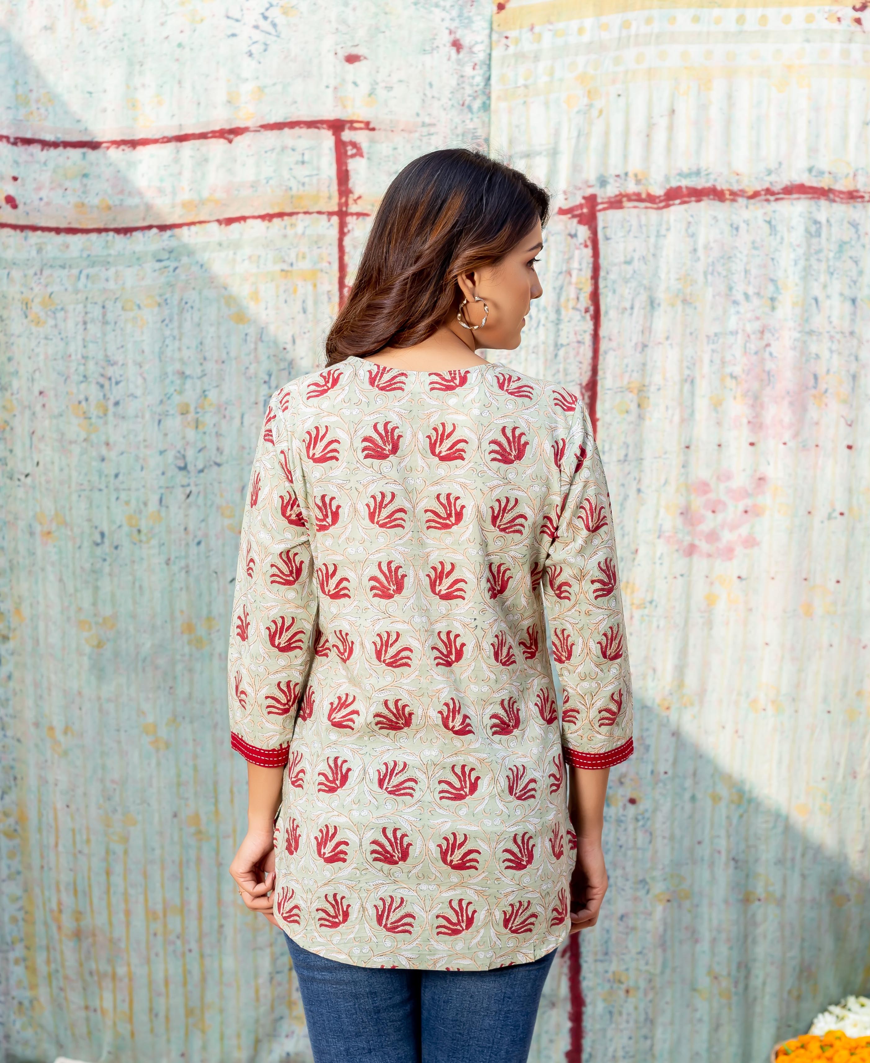 Rear view of model wearing a meadow green block printed top with red floral motifs.