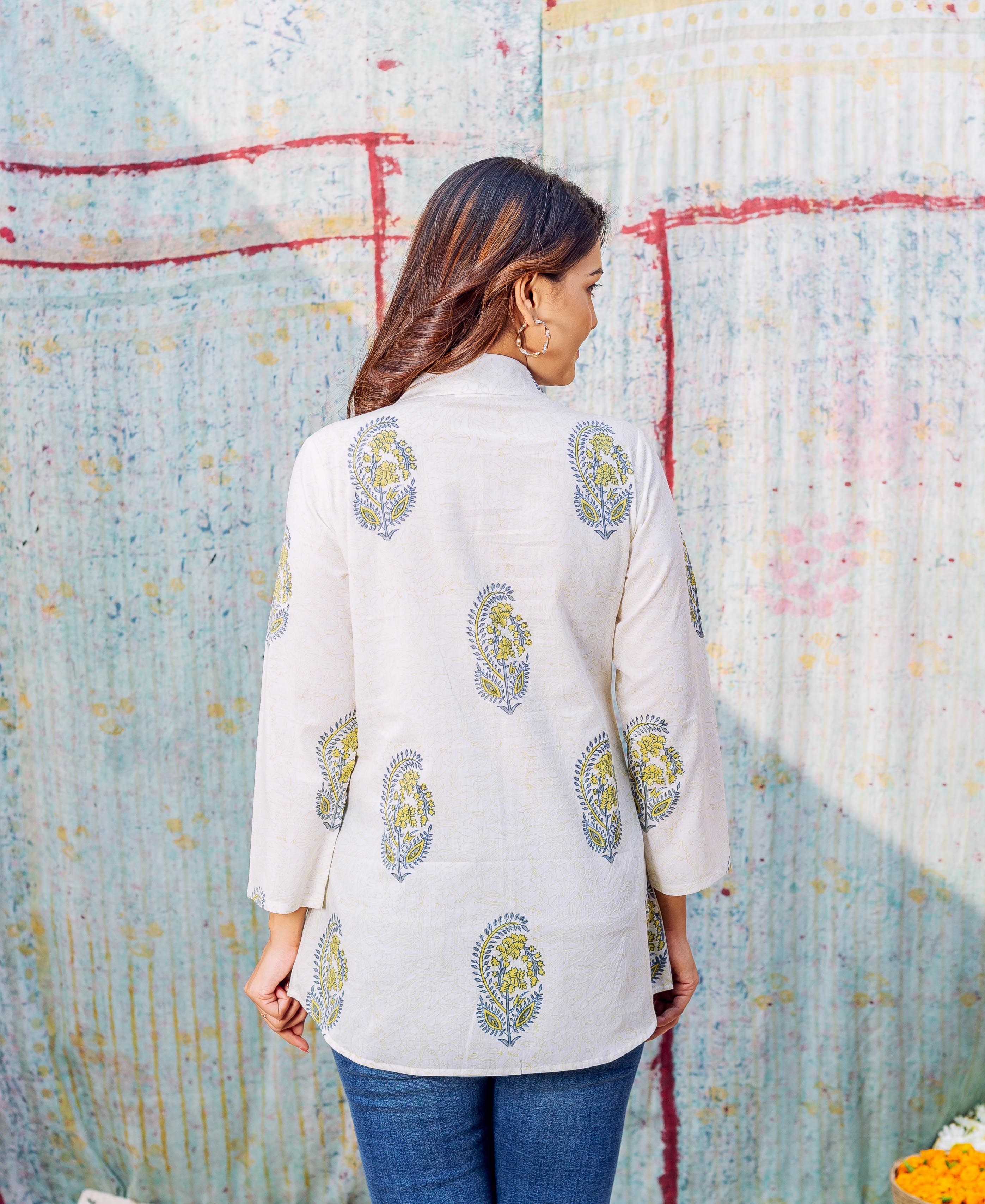 Model's back, ivory hand-block-printed tunic with scattered yellow and blue paisley motifs.