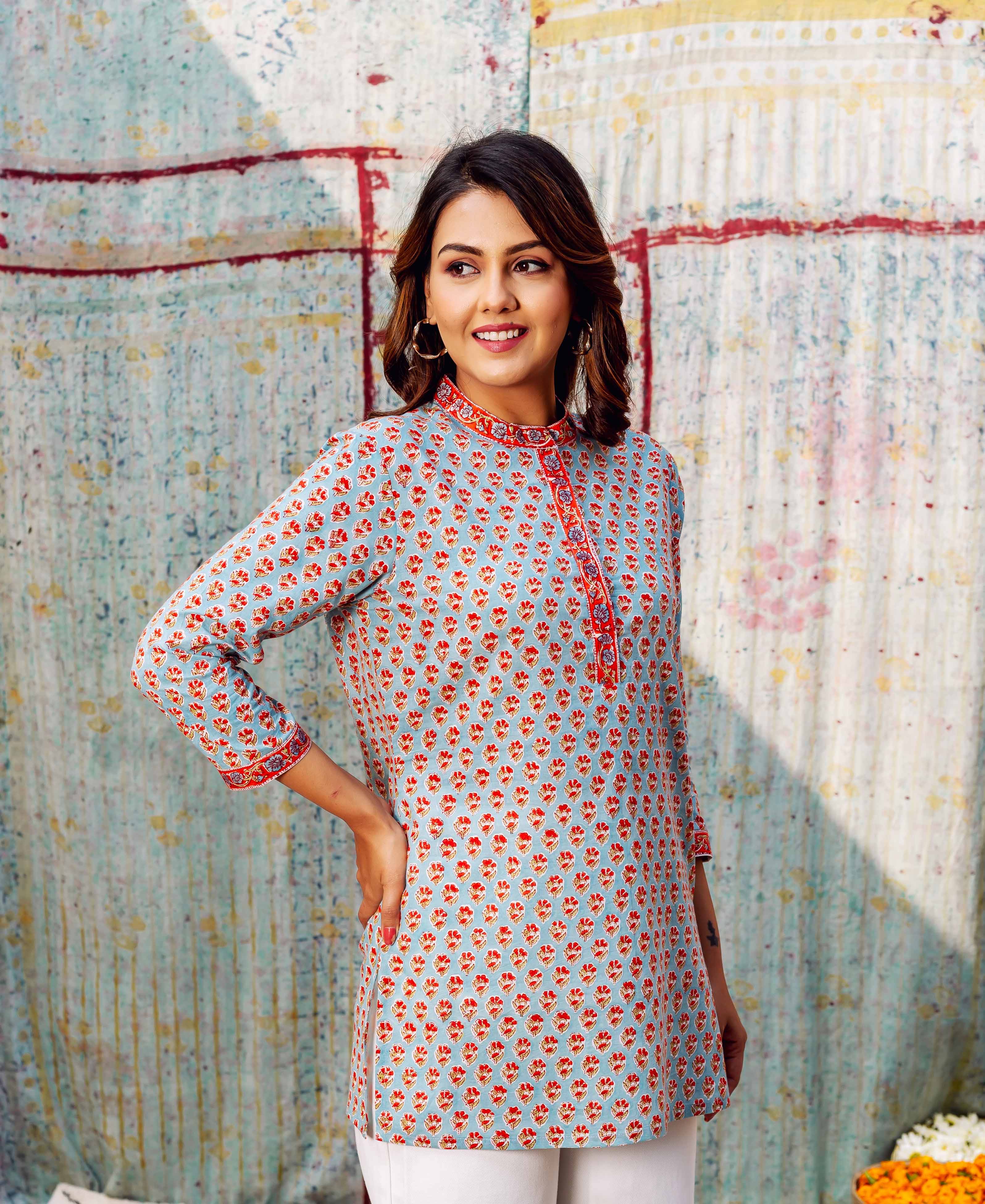 Model in front view wearing a light blue ethnic top with ashen orange booti print.