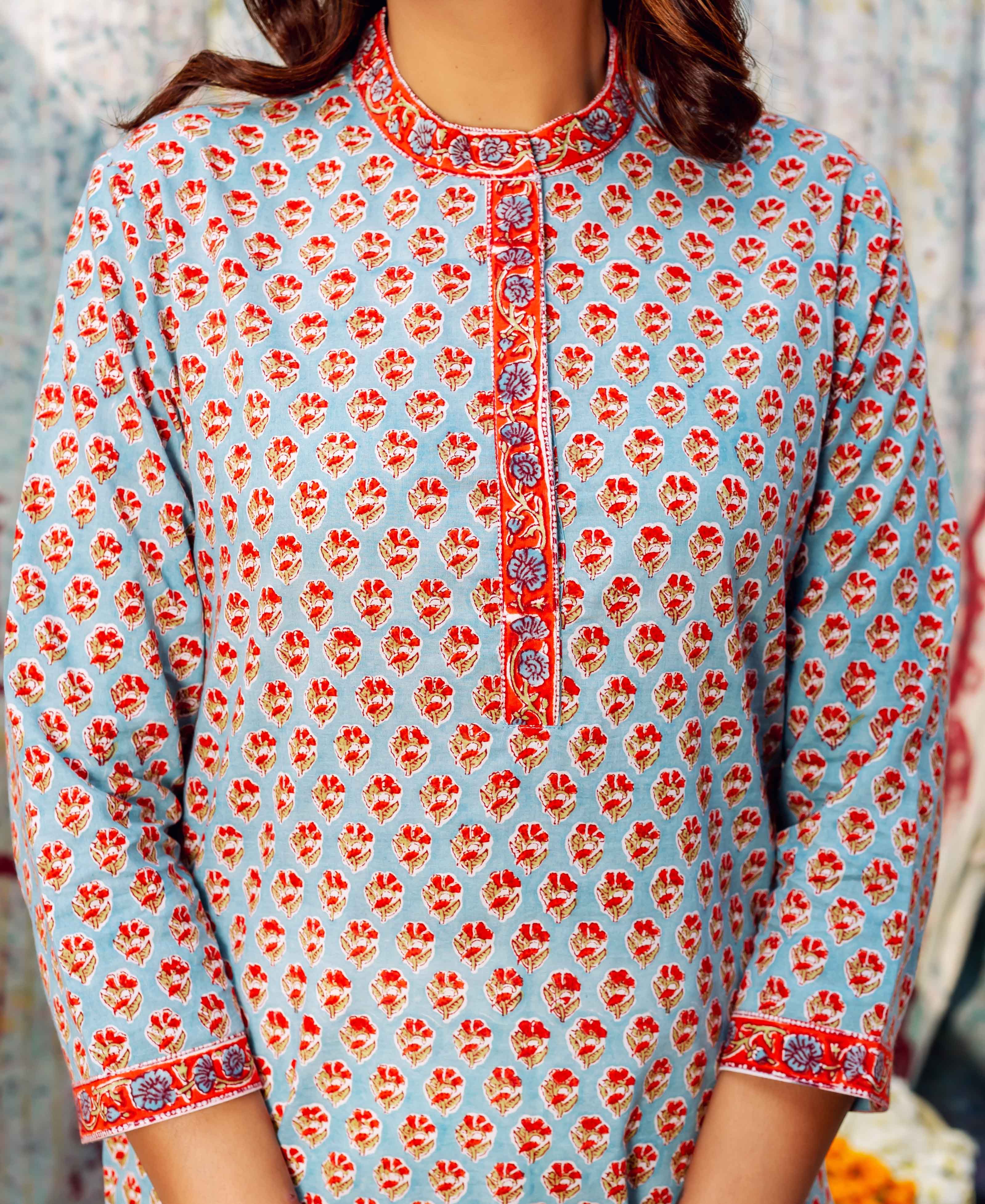 Front view of light blue cotton top with red booti print and orange floral trim.