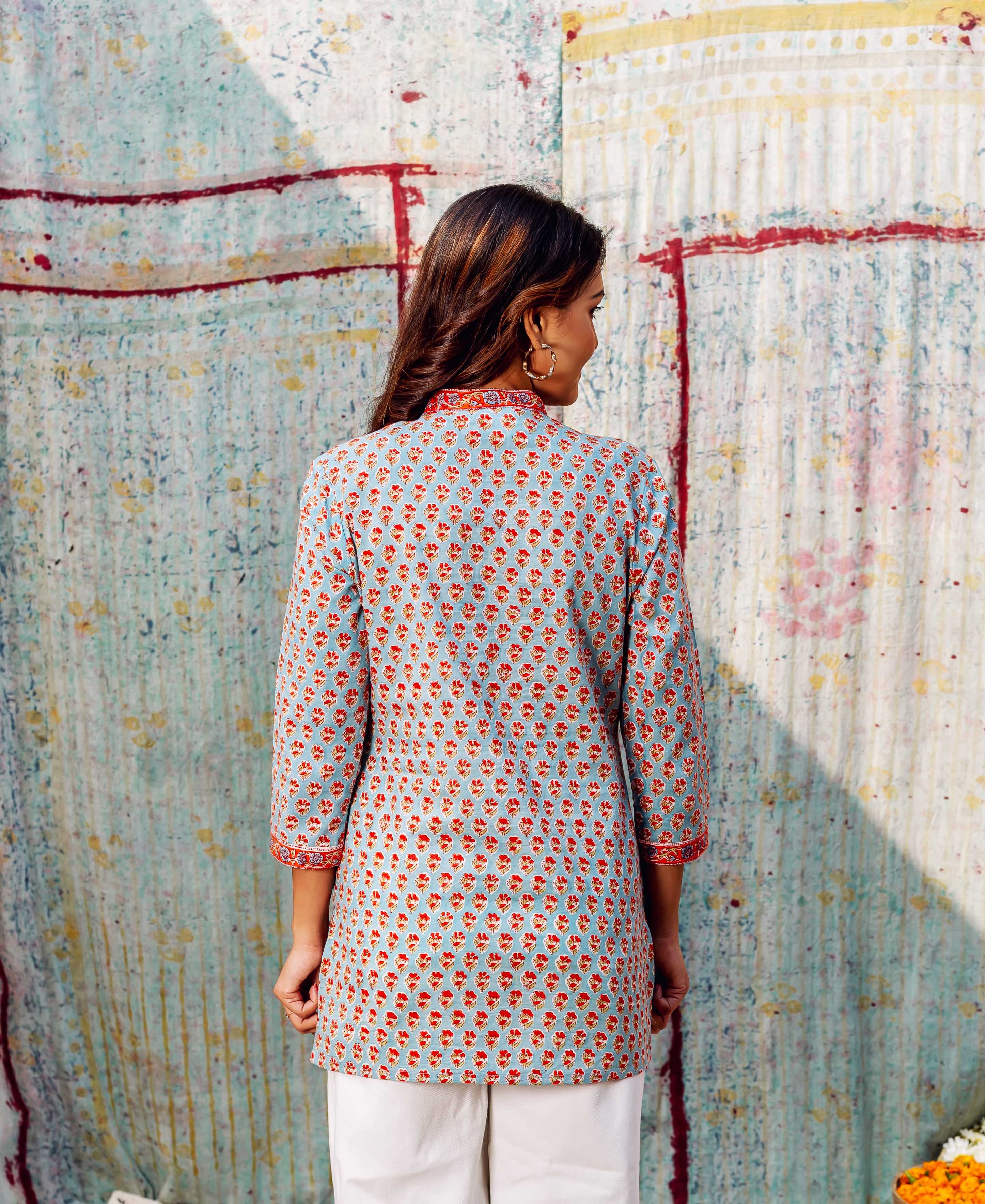 Back view: model wears light blue hand-block-printed ethnic top with ashen orange booti print.