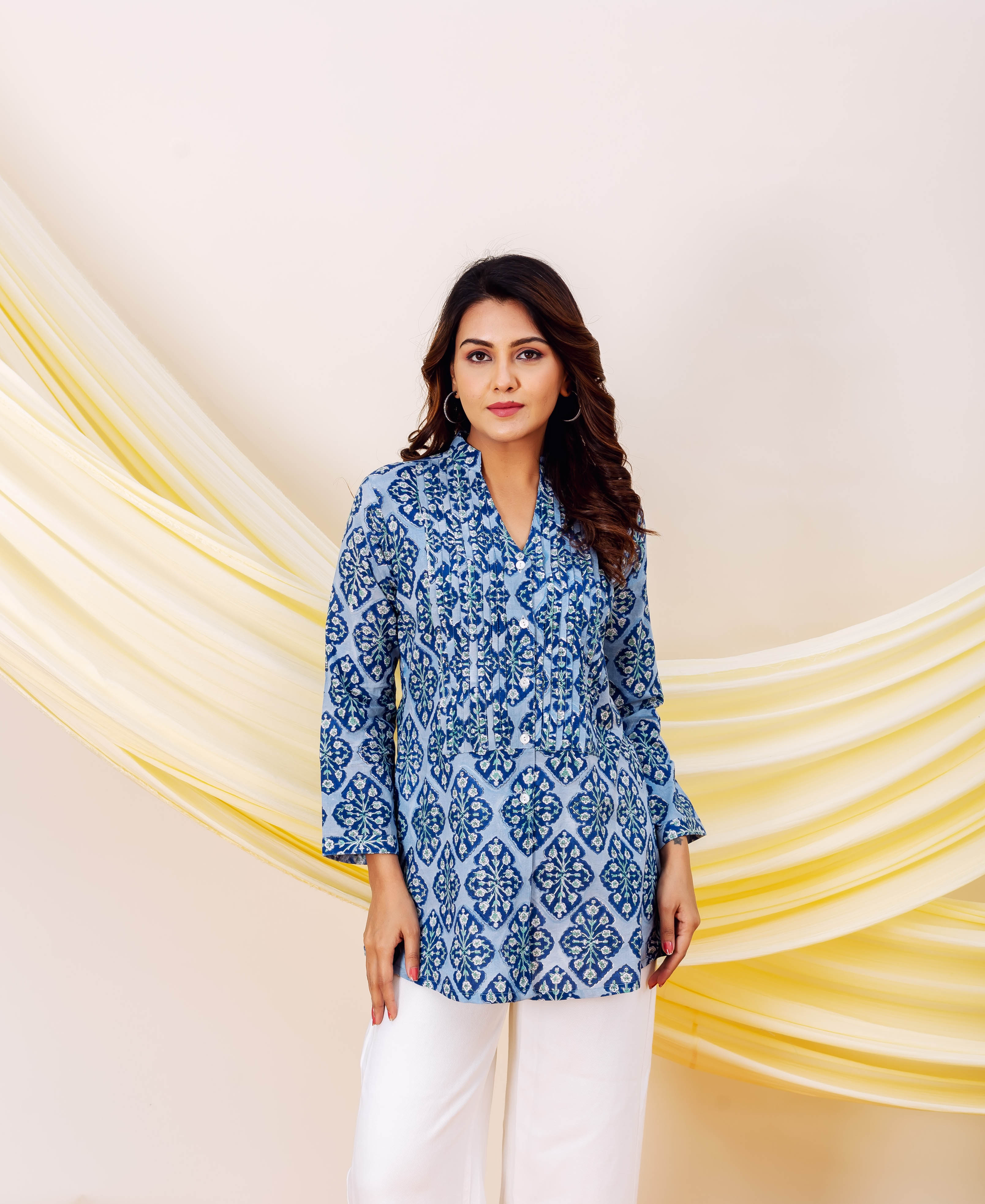 Front view of model wearing a blue and white patterned hand-printed top and white pants.