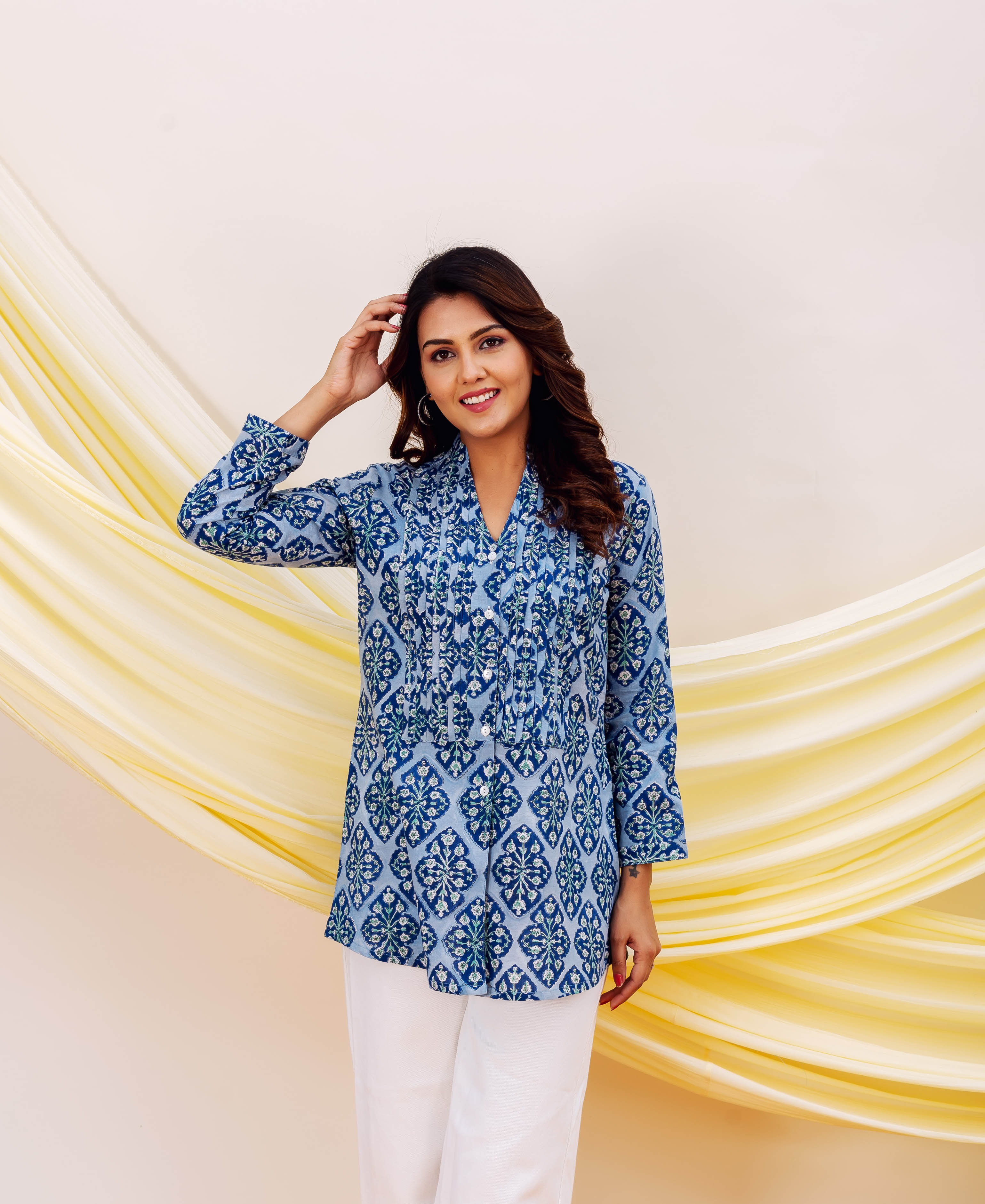 Smiling model in a blue and white hand-block printed ethnic top, front view.