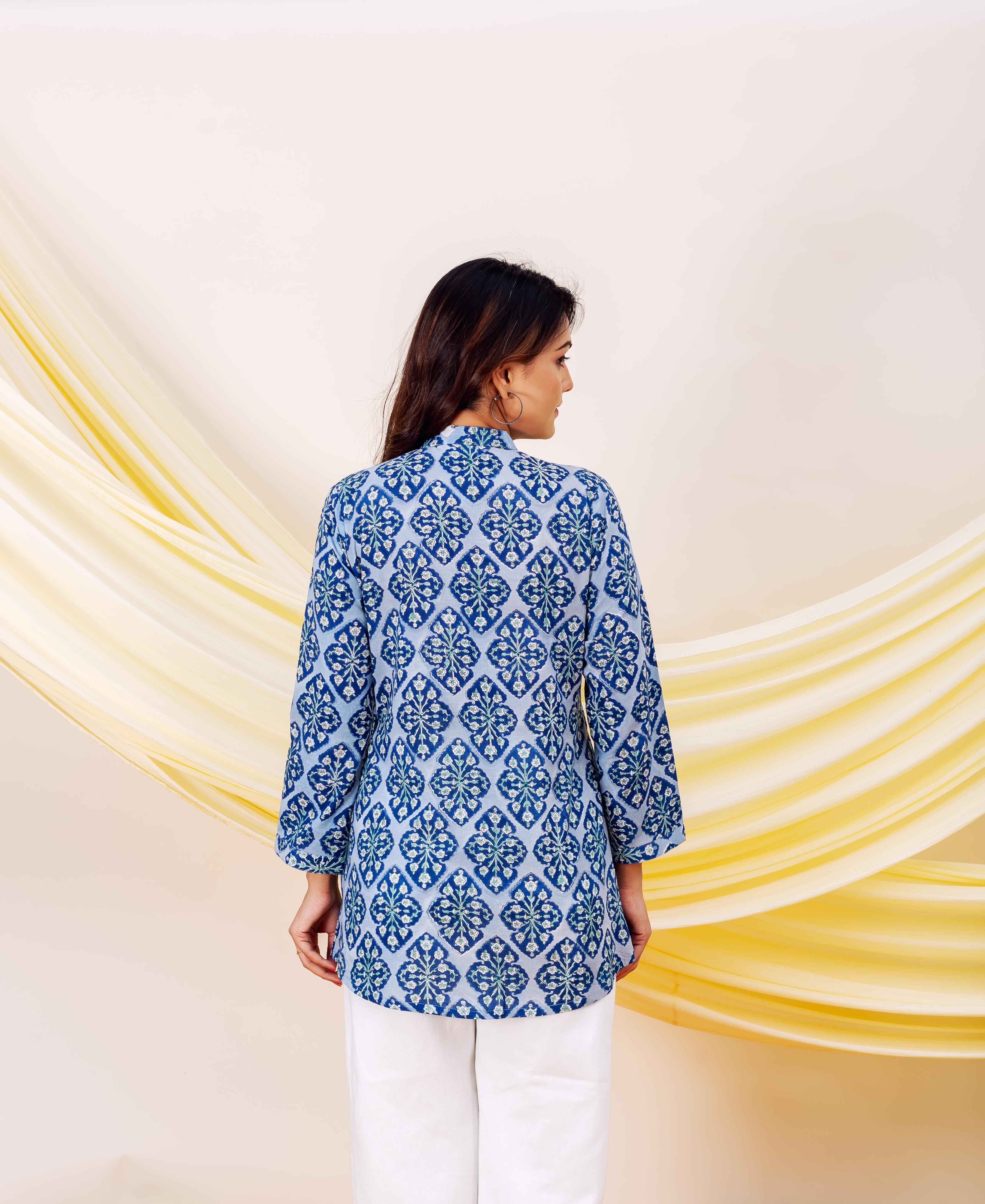 Model seen from back wearing a blue and white patterned top with geometric floral print.