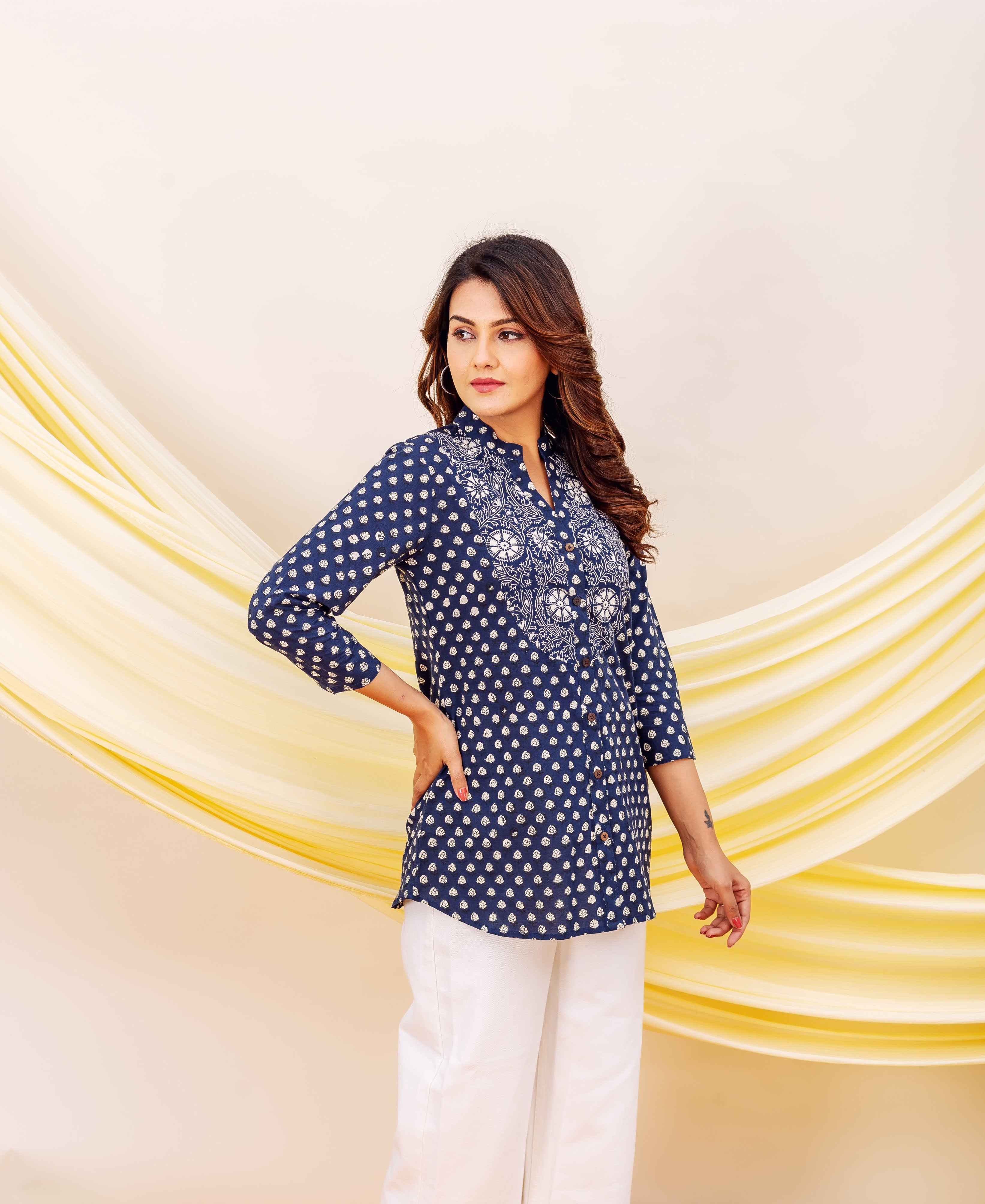 A model wearing a blue and white printed top with a floral pattern.