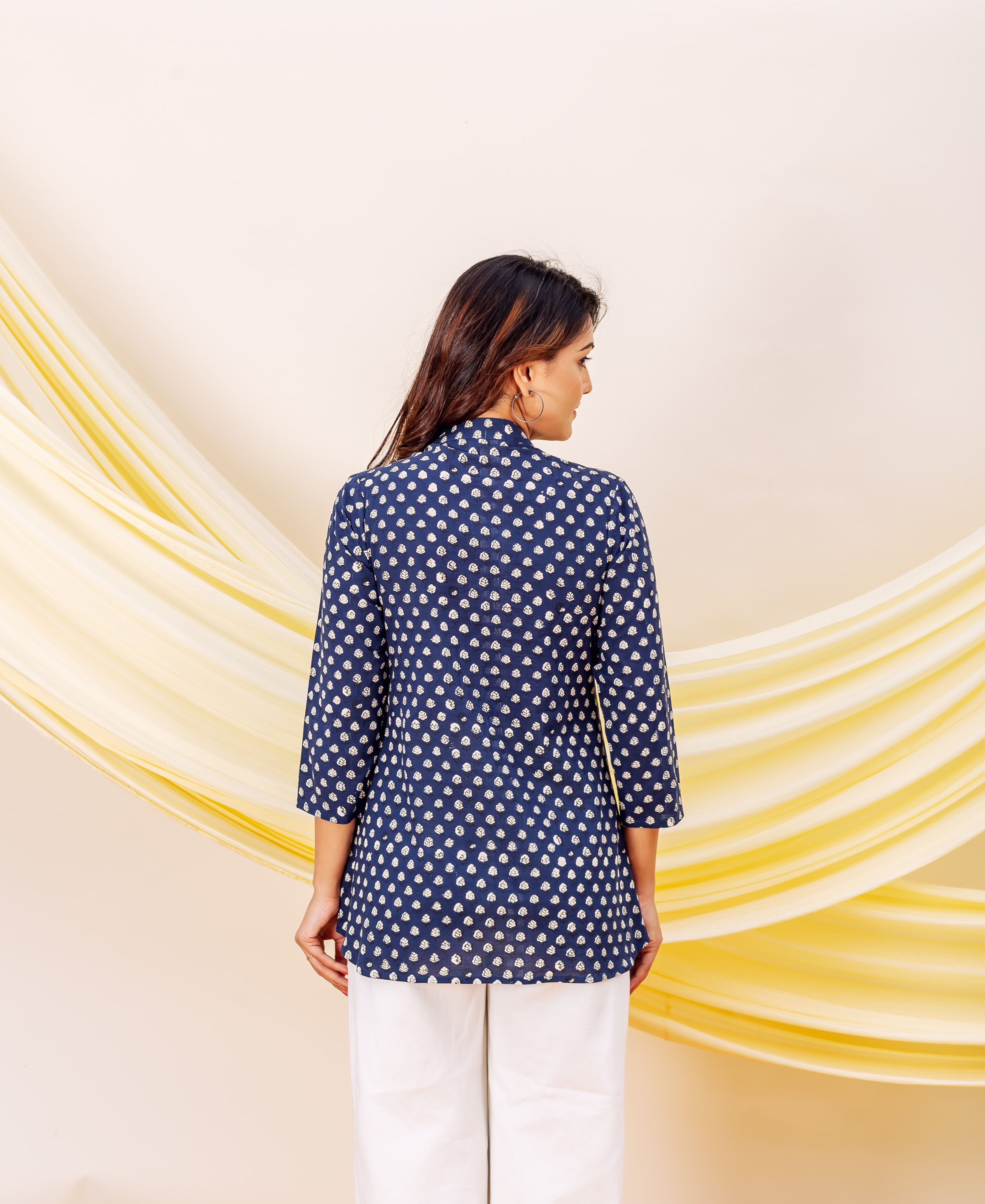Back view: model in indigo booti printed cotton top with white pants.