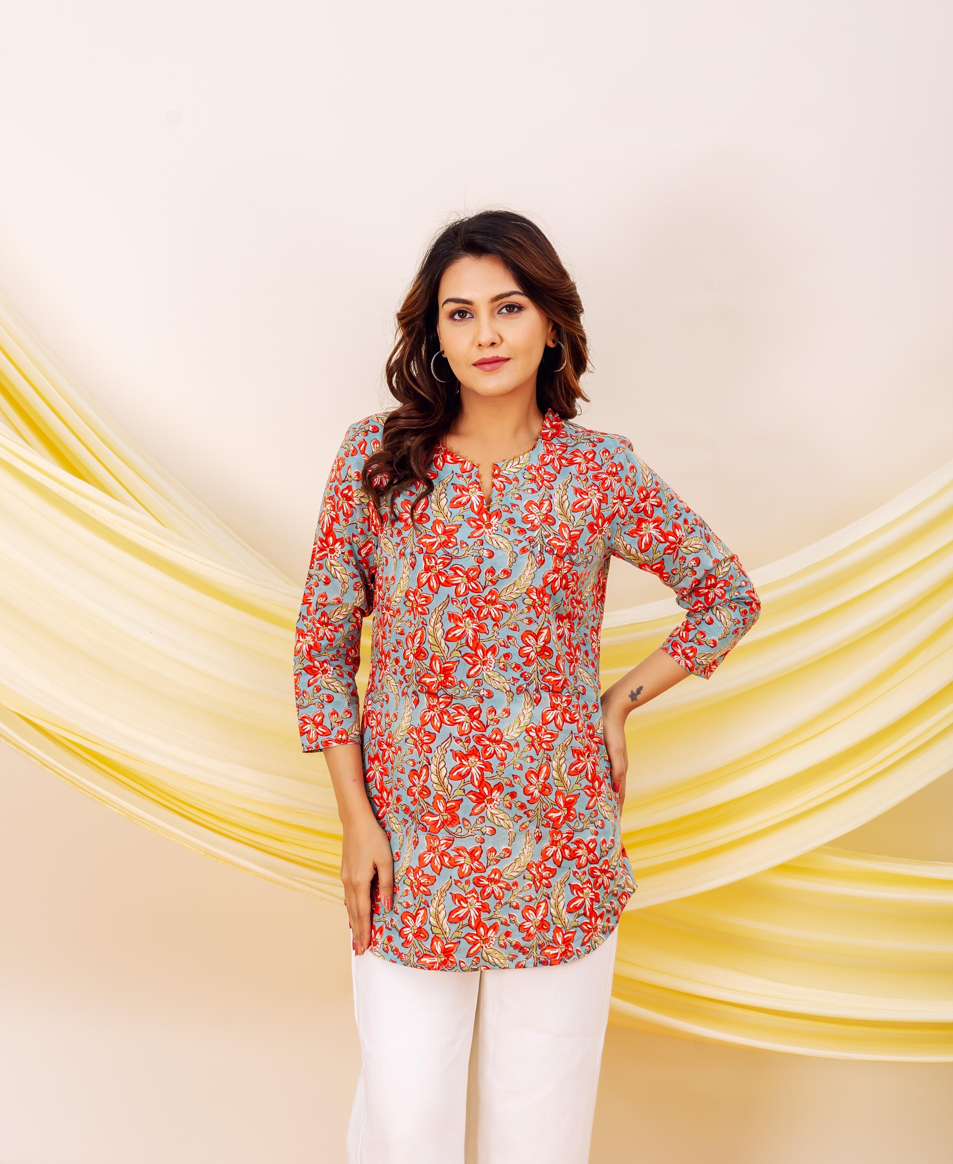 A woman models a vibrant red and blue floral print cotton top with a keyhole neckline.