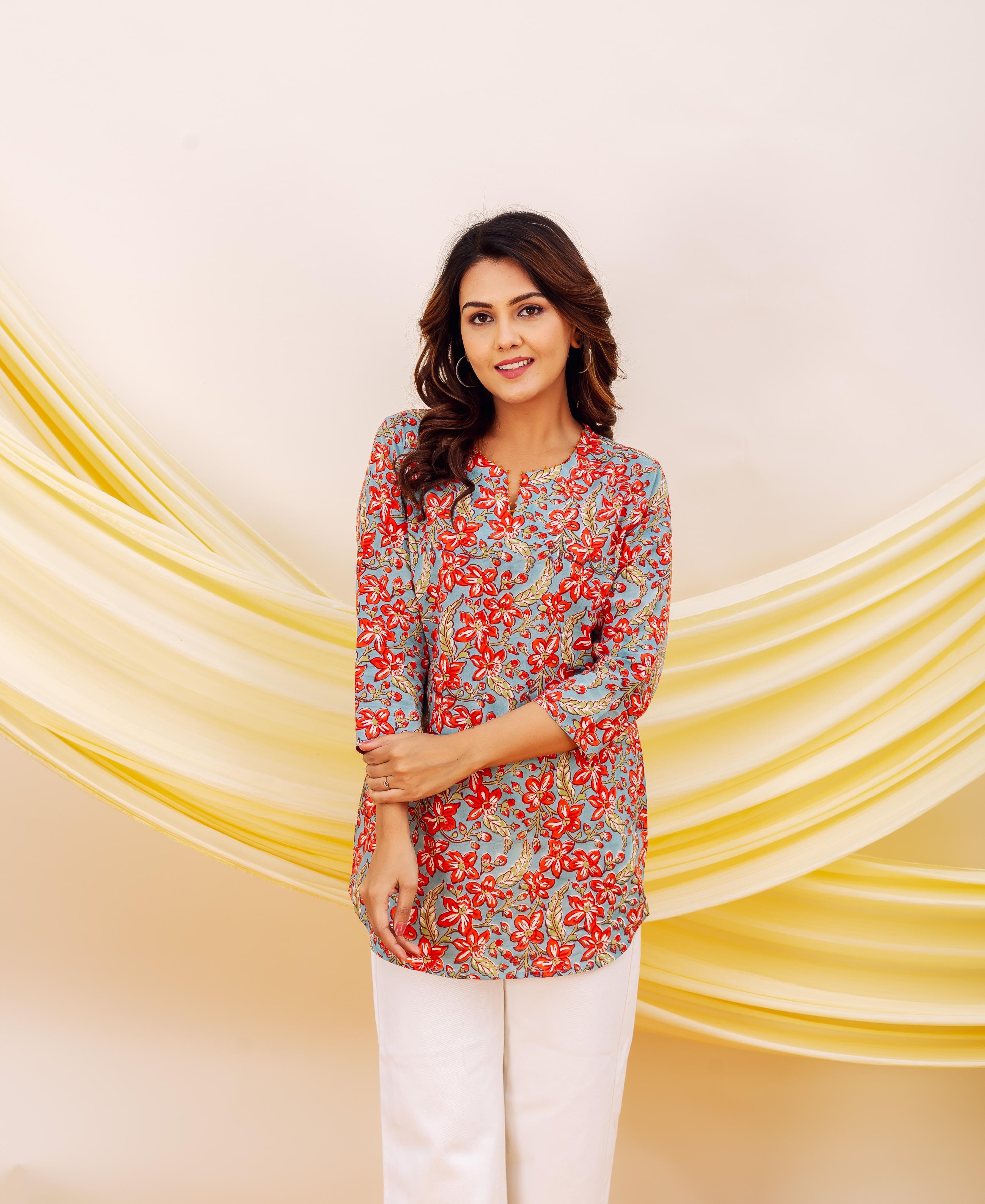 Front view of model in red and blue floral printed cotton top, white pants.