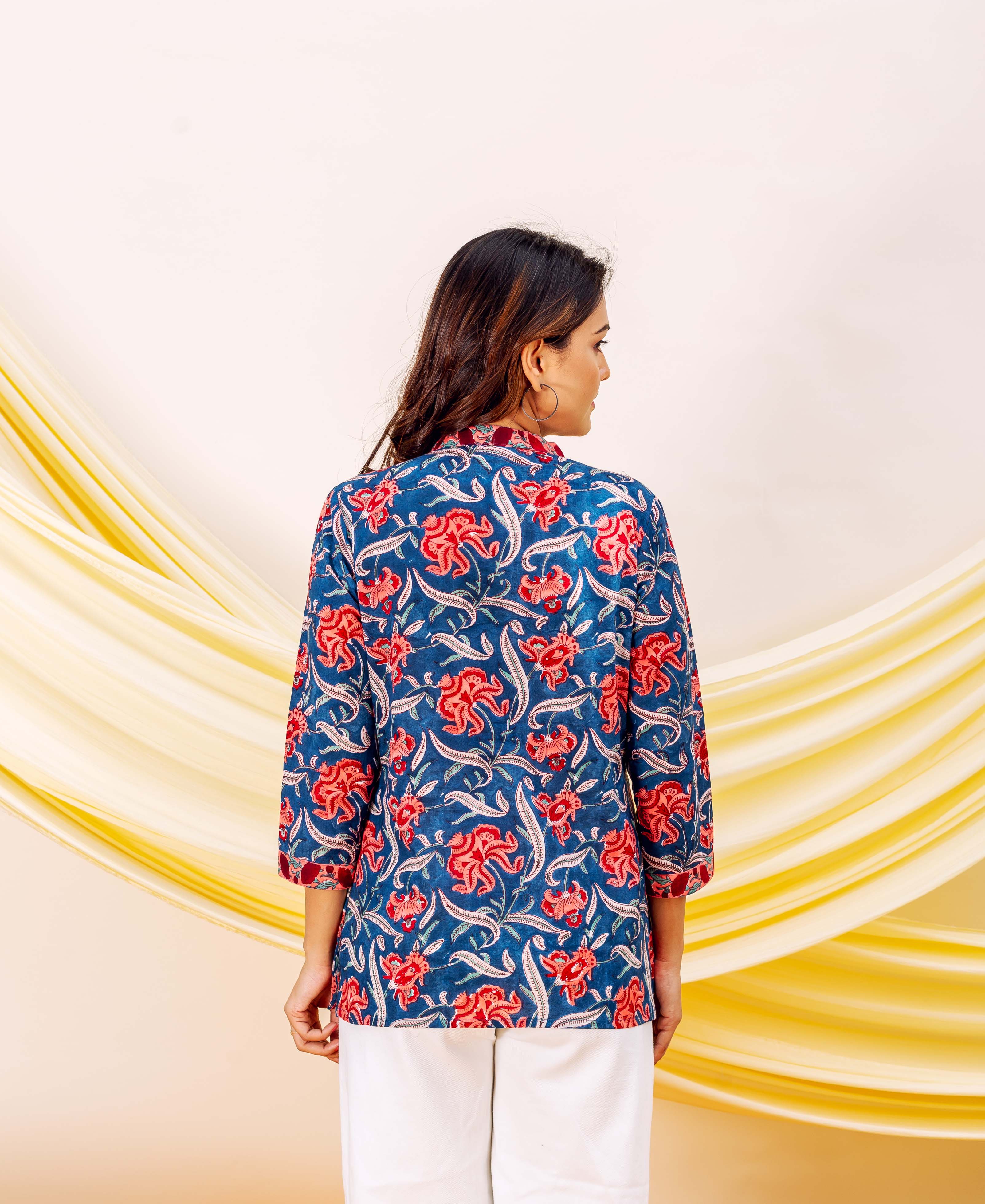 Back view of model wearing a blue hand-block-printed floral top with scarlet red petals.