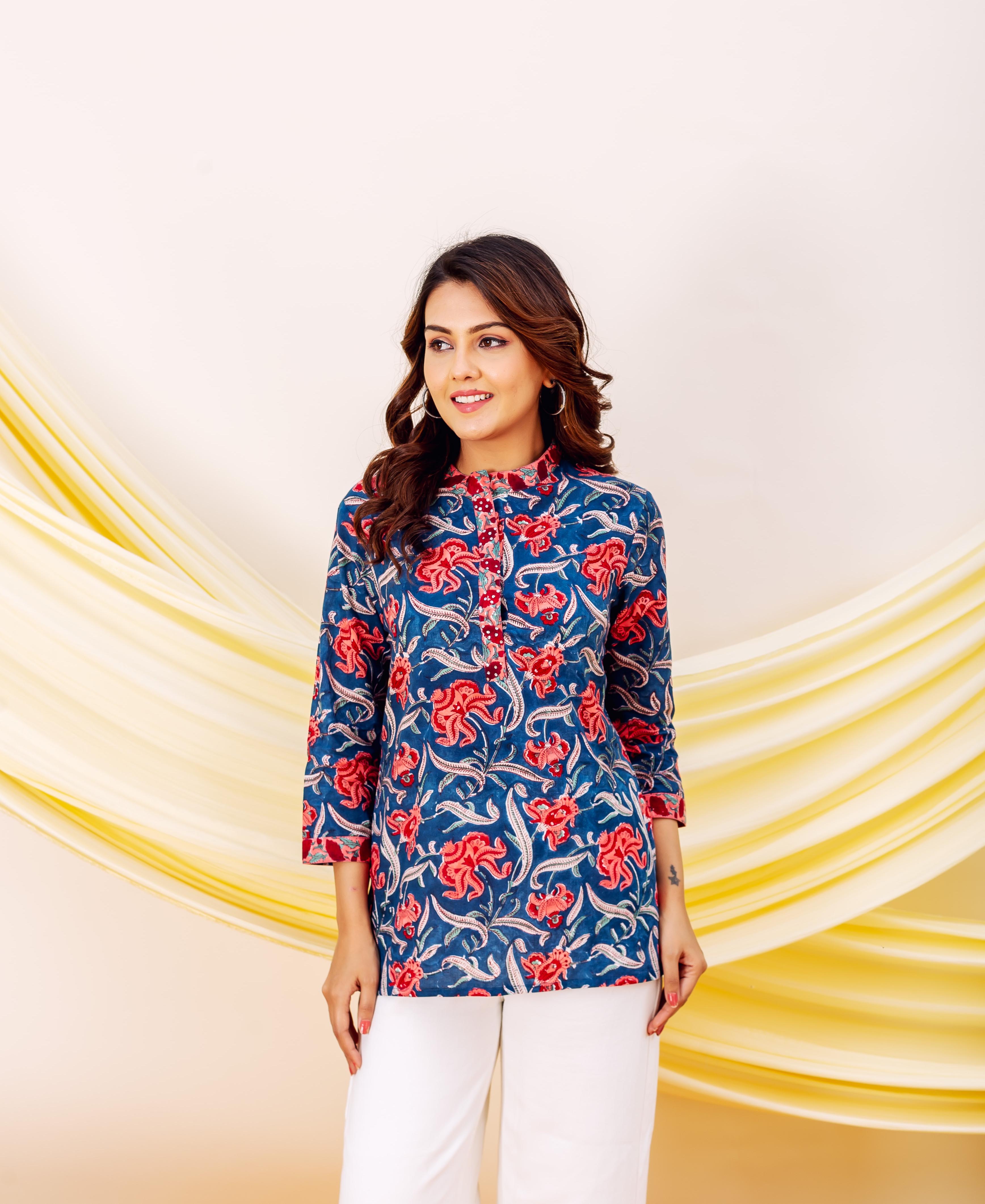 Smiling model wearing a blue hand-block printed top with red floral designs and white pants.
