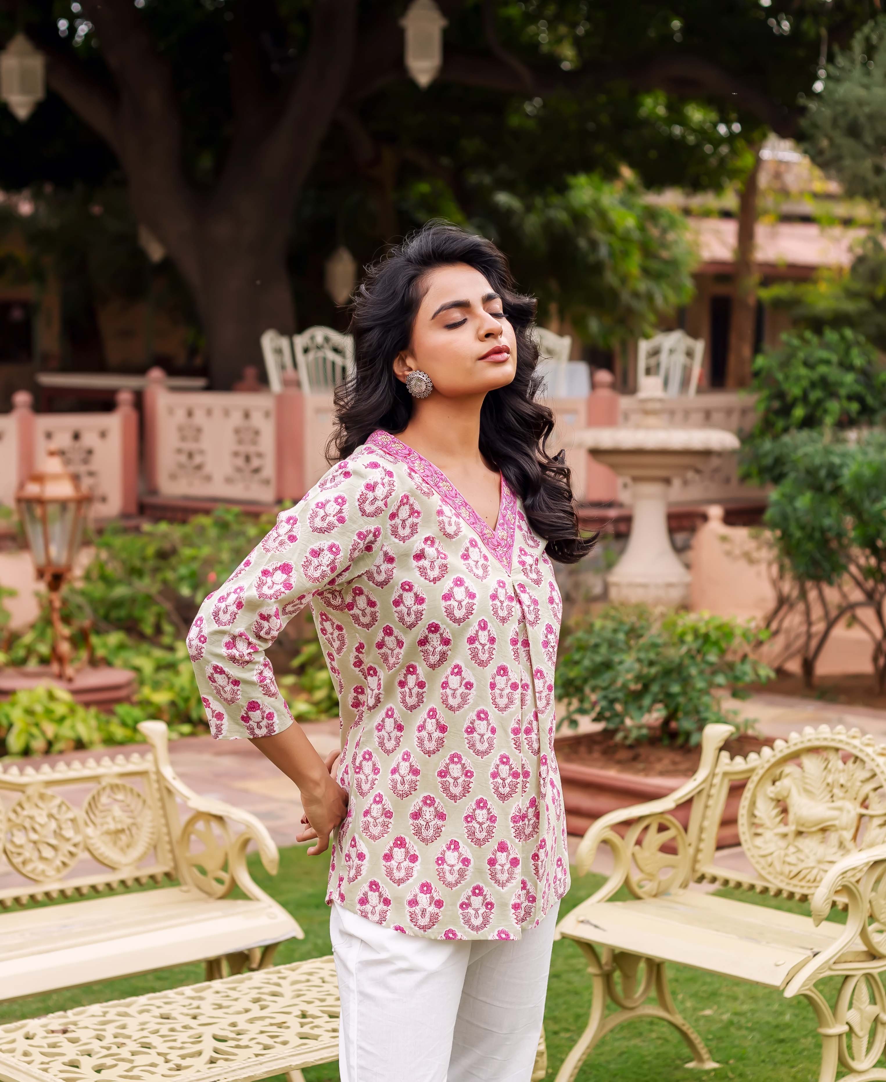 Three-quarter shot of model in a mint and pink block printed tunic with white pants.