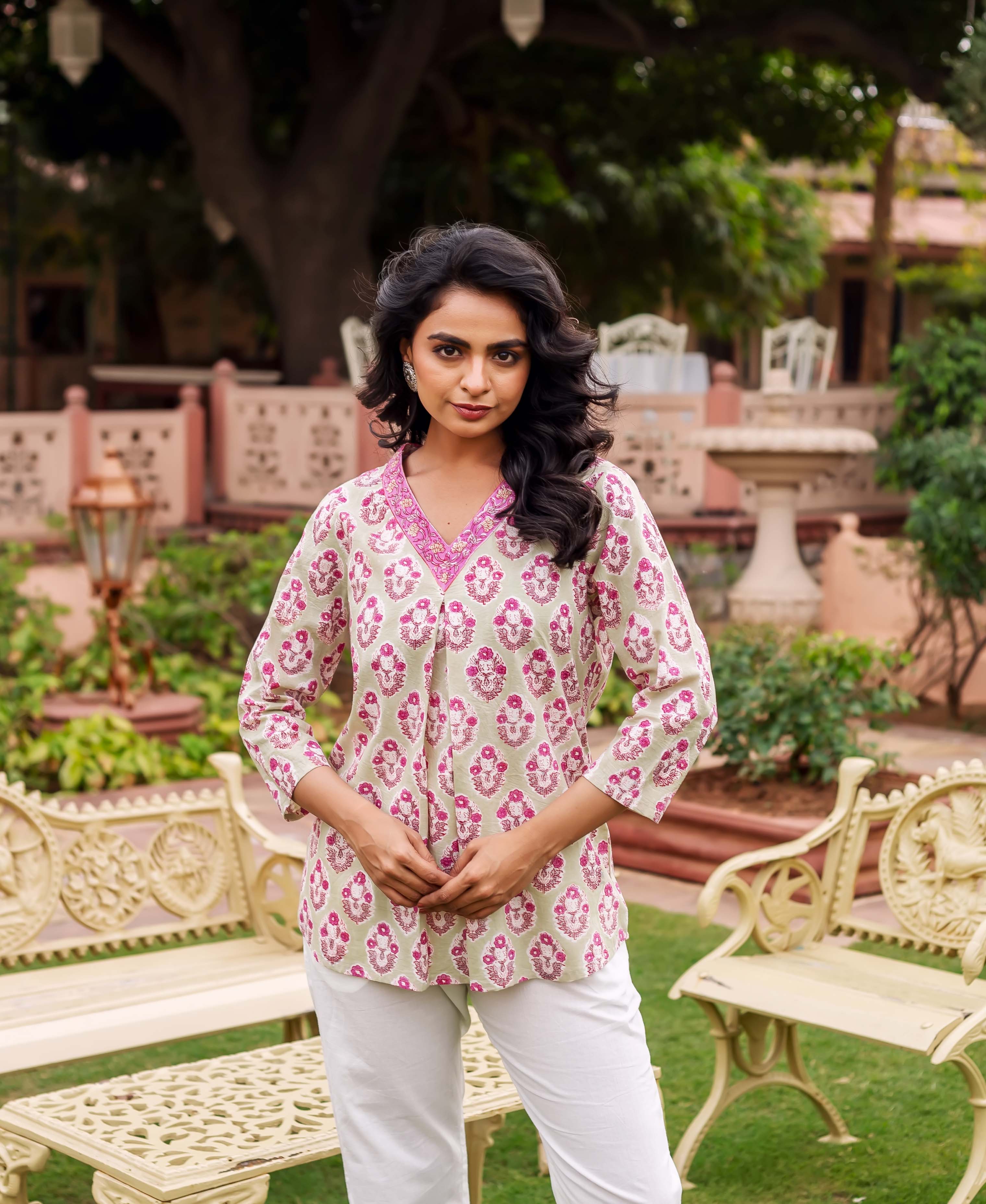 A woman wearing a mint green tunic with pink floral block print.