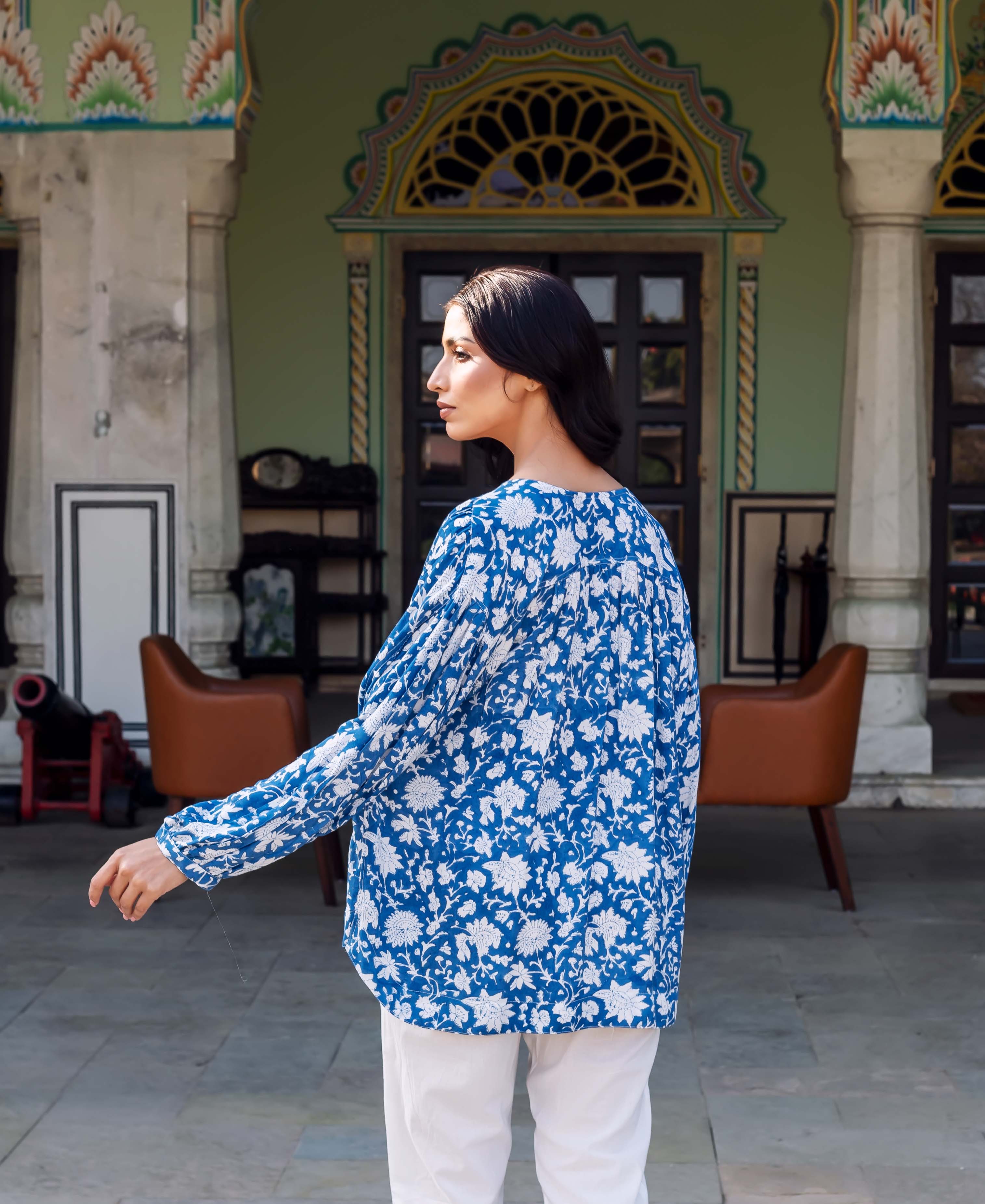 Back view of woman wearing a loose blue tunic with white hand-block floral print.